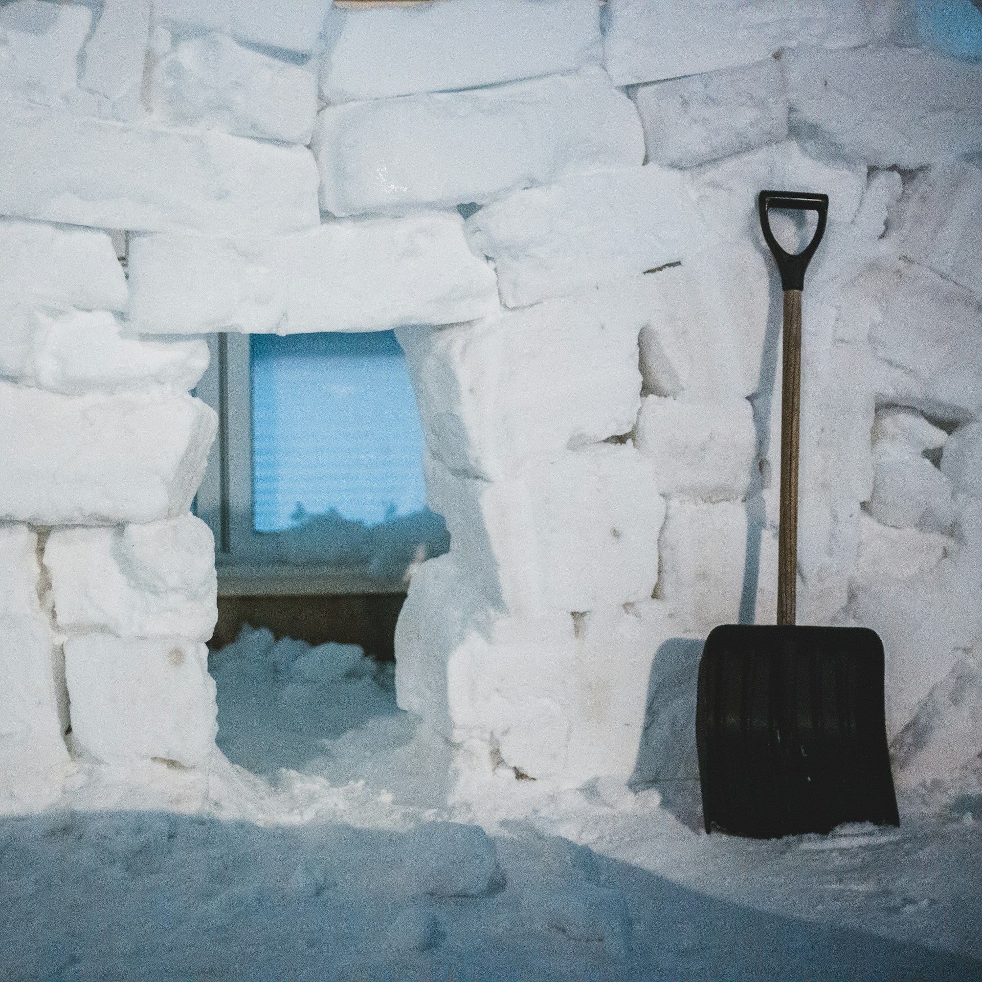 Winter home prep snow shovel leaning against a wall of packed snow