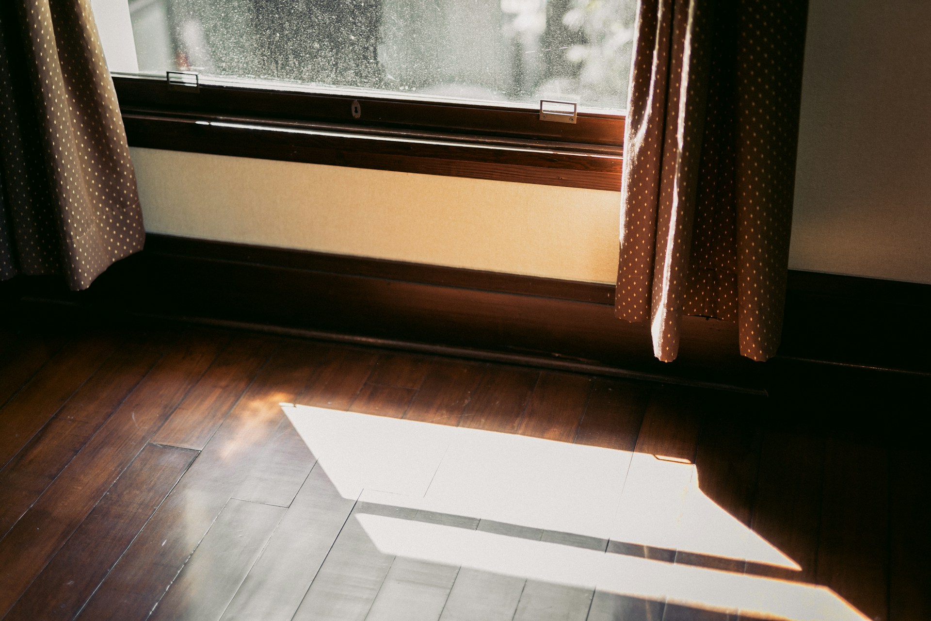 Winter sunlight pouring through open curtains onto a wooden floor
