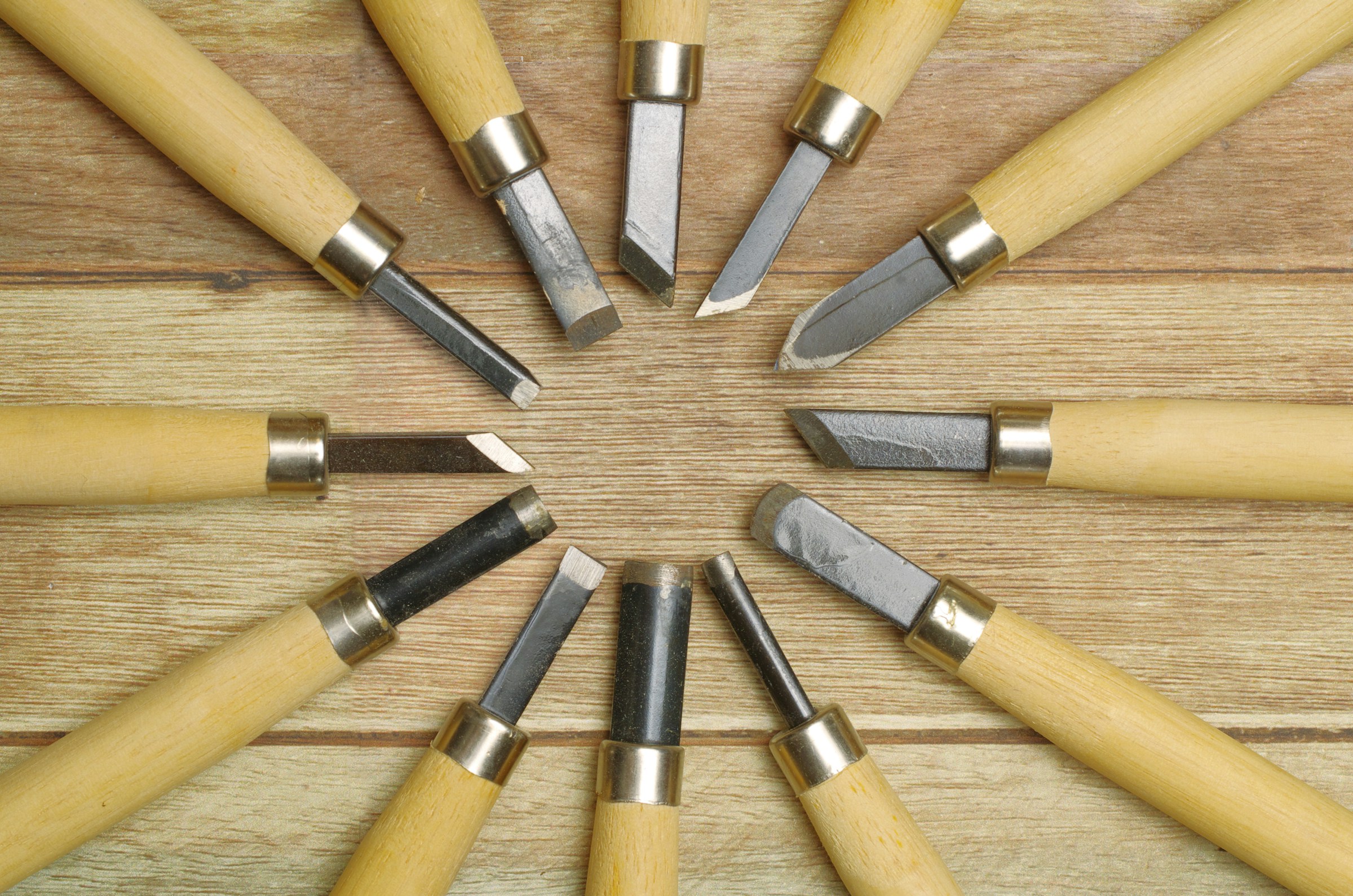 Wood carving gouges with pale handles laid out in a circle