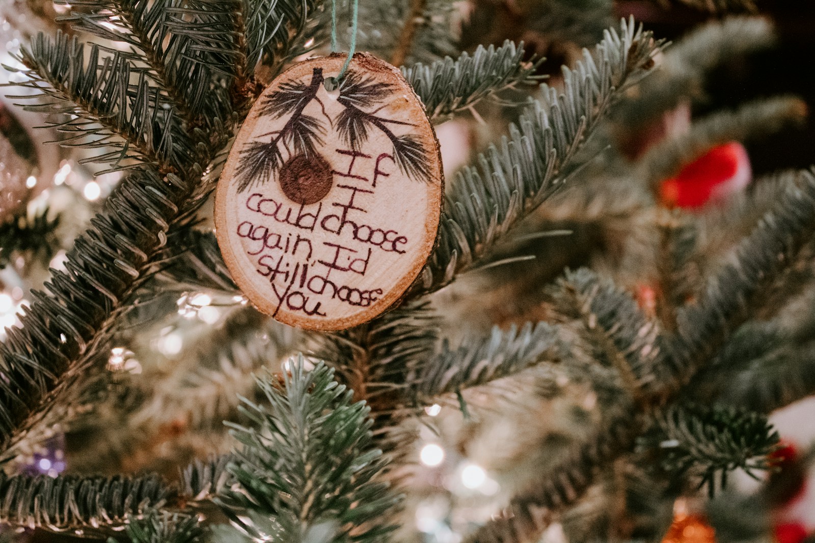 Christmas table favors of a wood slice ornament with a handwritten message hanging on a tree