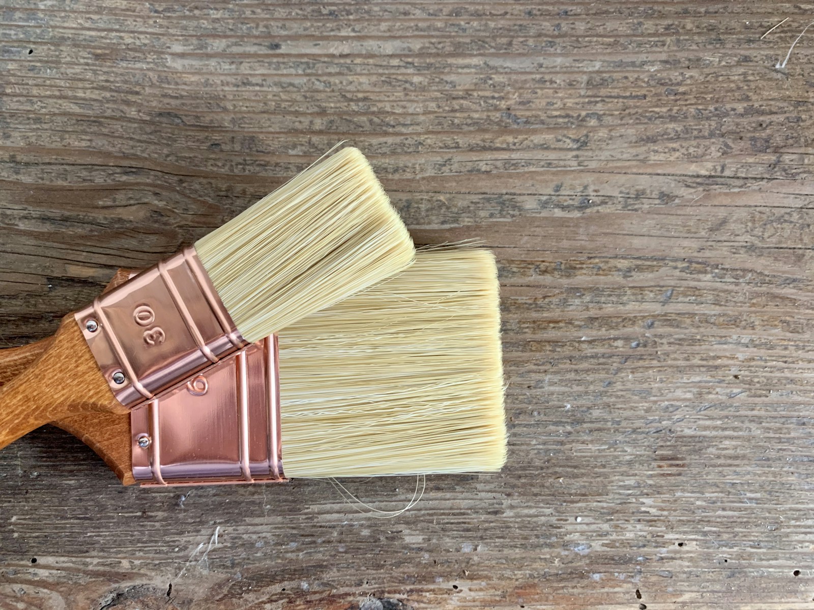 Two paint brushes resting on a rustic board