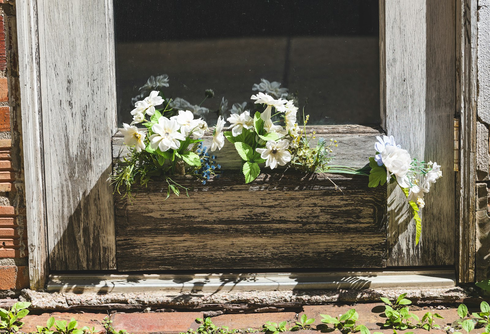Wooden window box front porch planters with white flowers on a weathered wall