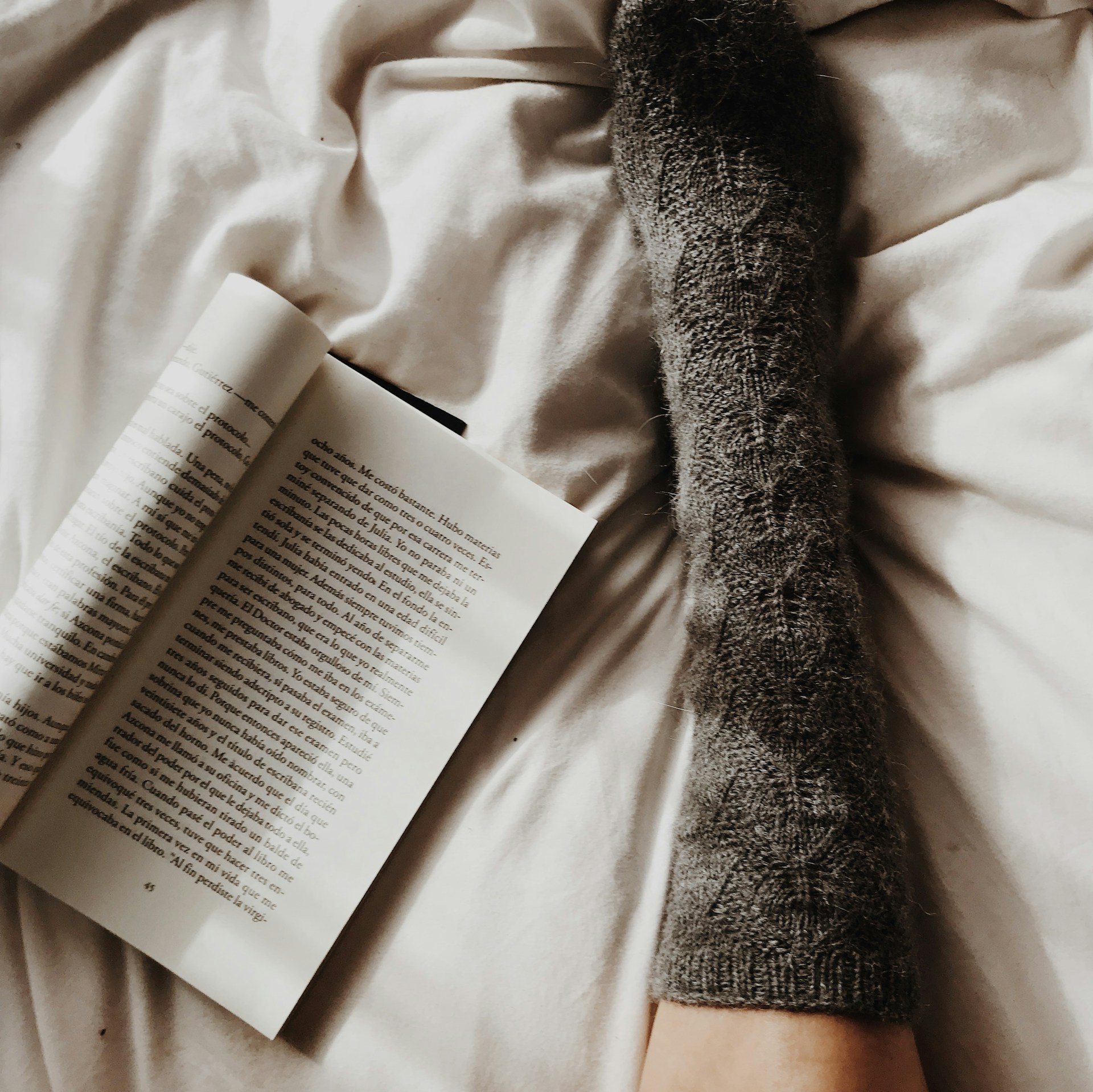 Thick wool sock on a bed with an open book