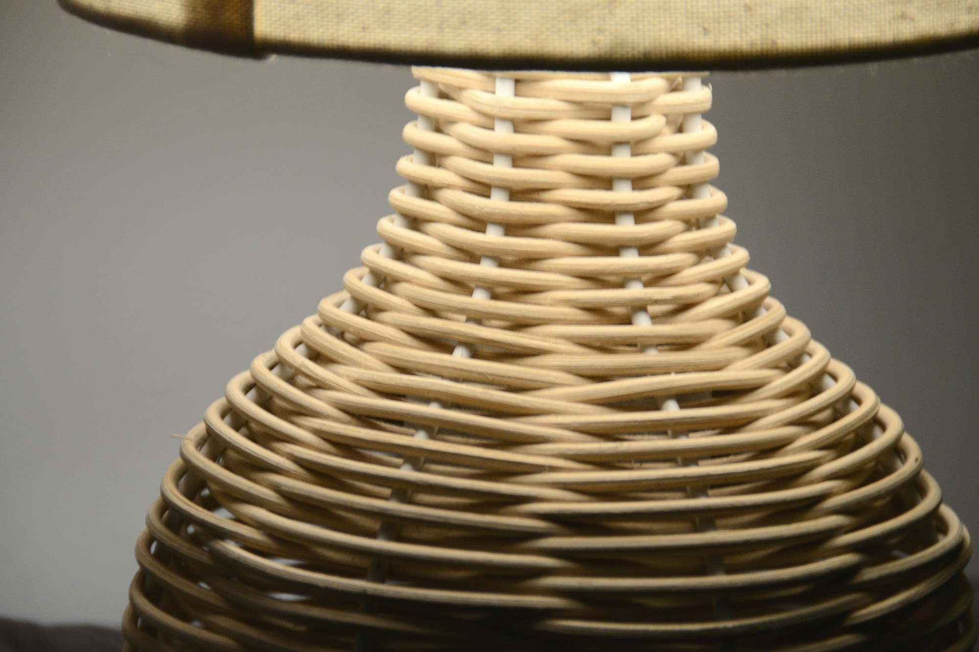 Close up of a lamp base wrapped in rows of natural cord under a fabric shade