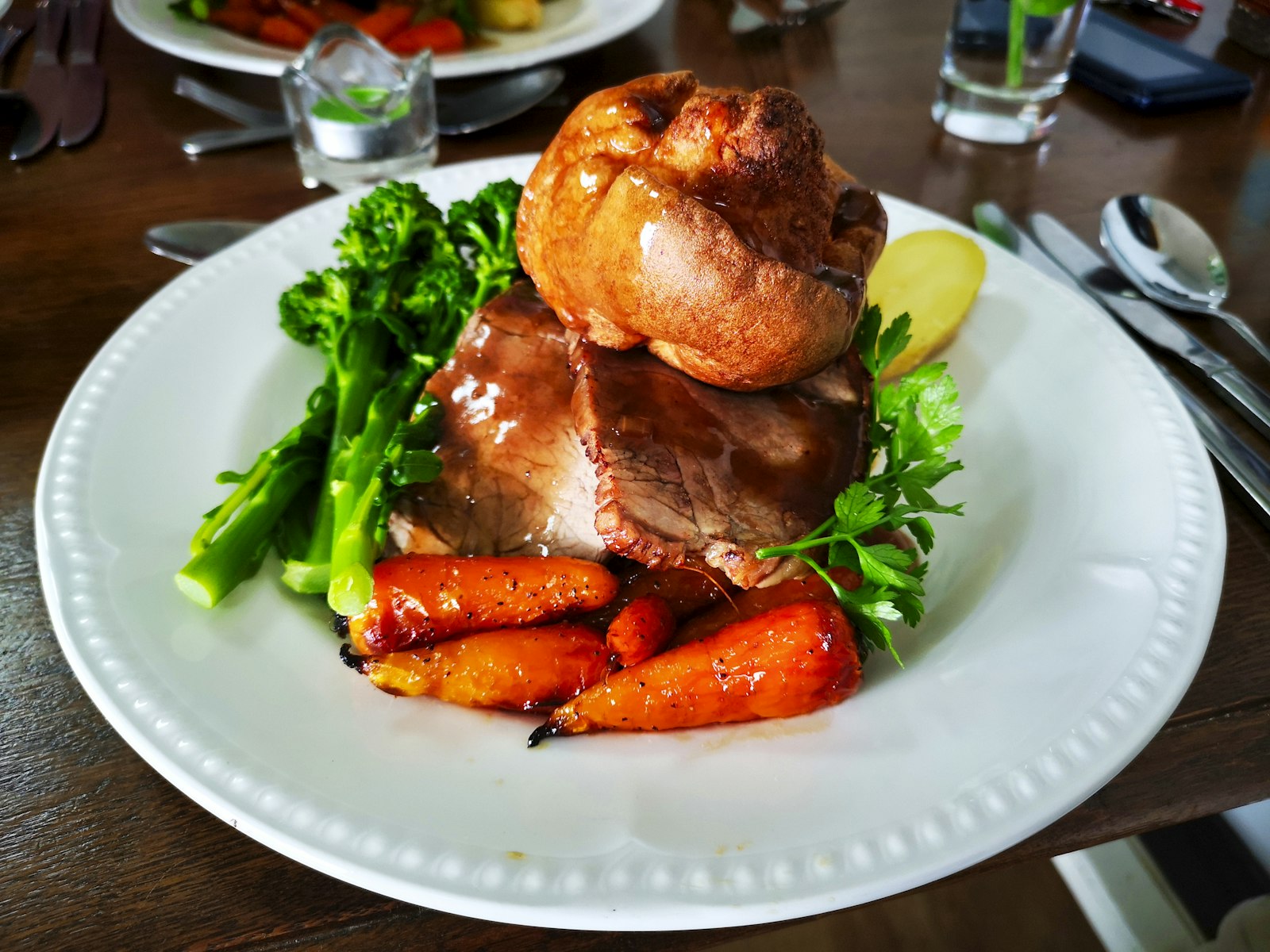 Slow cooker dinners: tender pot roast with roasted carrots and greens on a white plate