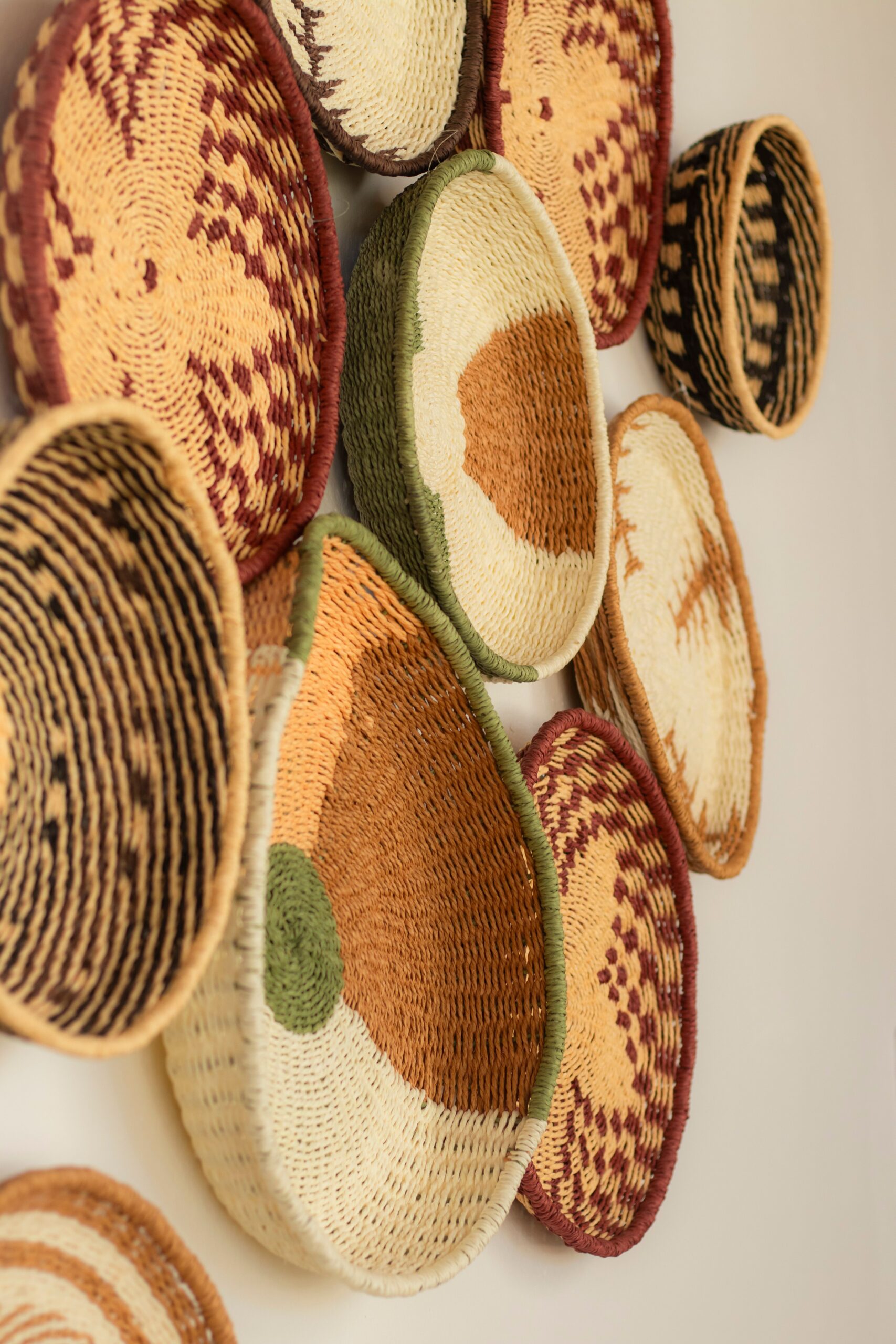 Round woven wall baskets with natural, terracotta, cream and dark geometric patterns.