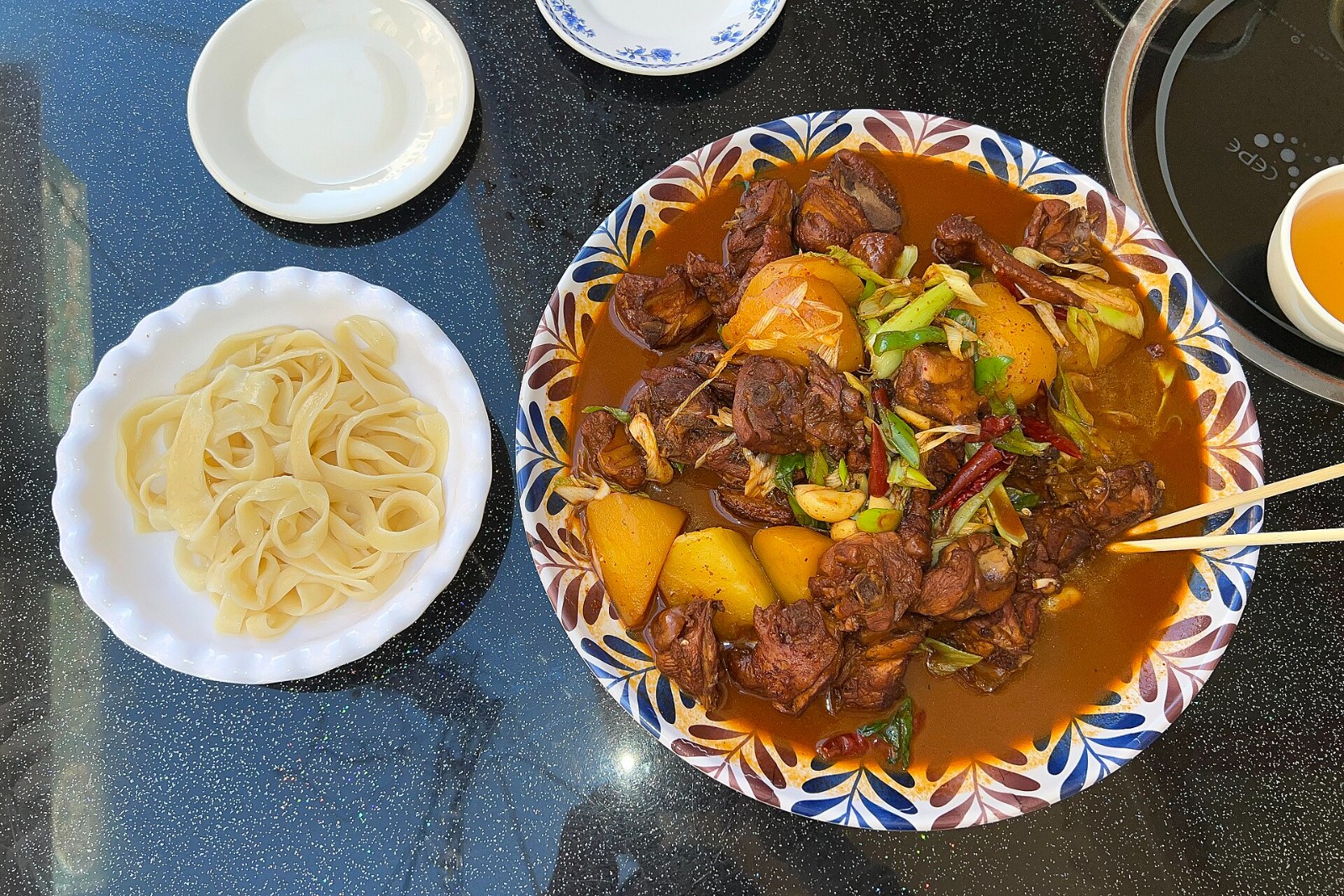 Big plate dapanji with potato chunks, peppers and wide noodles on the side