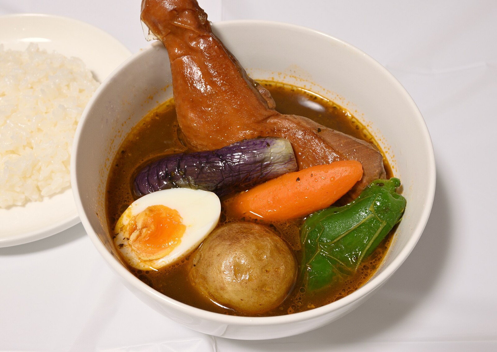 Japanese soup curry with a braised leg, whole potato, egg and vegetables