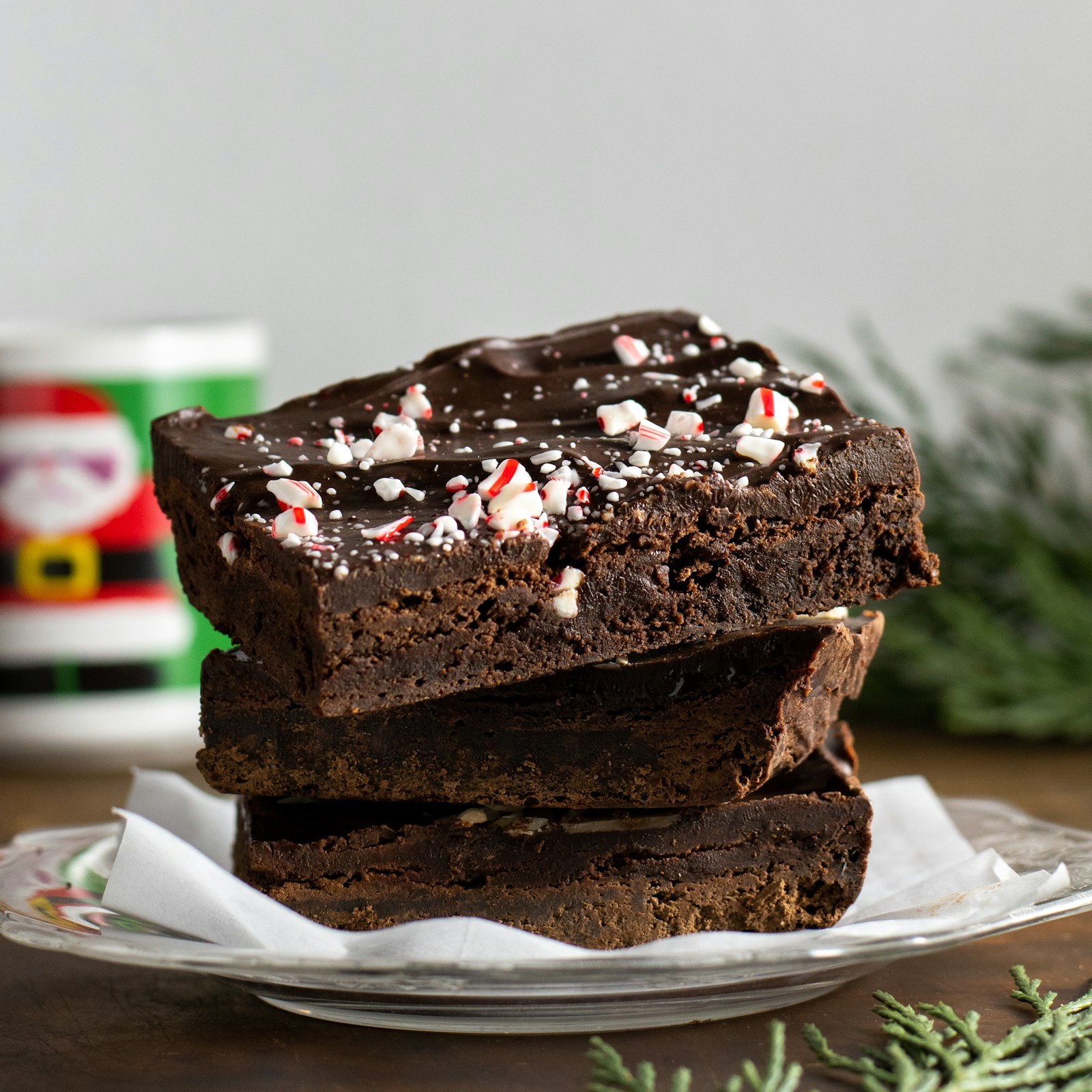 Stacked fudgy peppermint brownie bars topped with chocolate and crushed candy cane