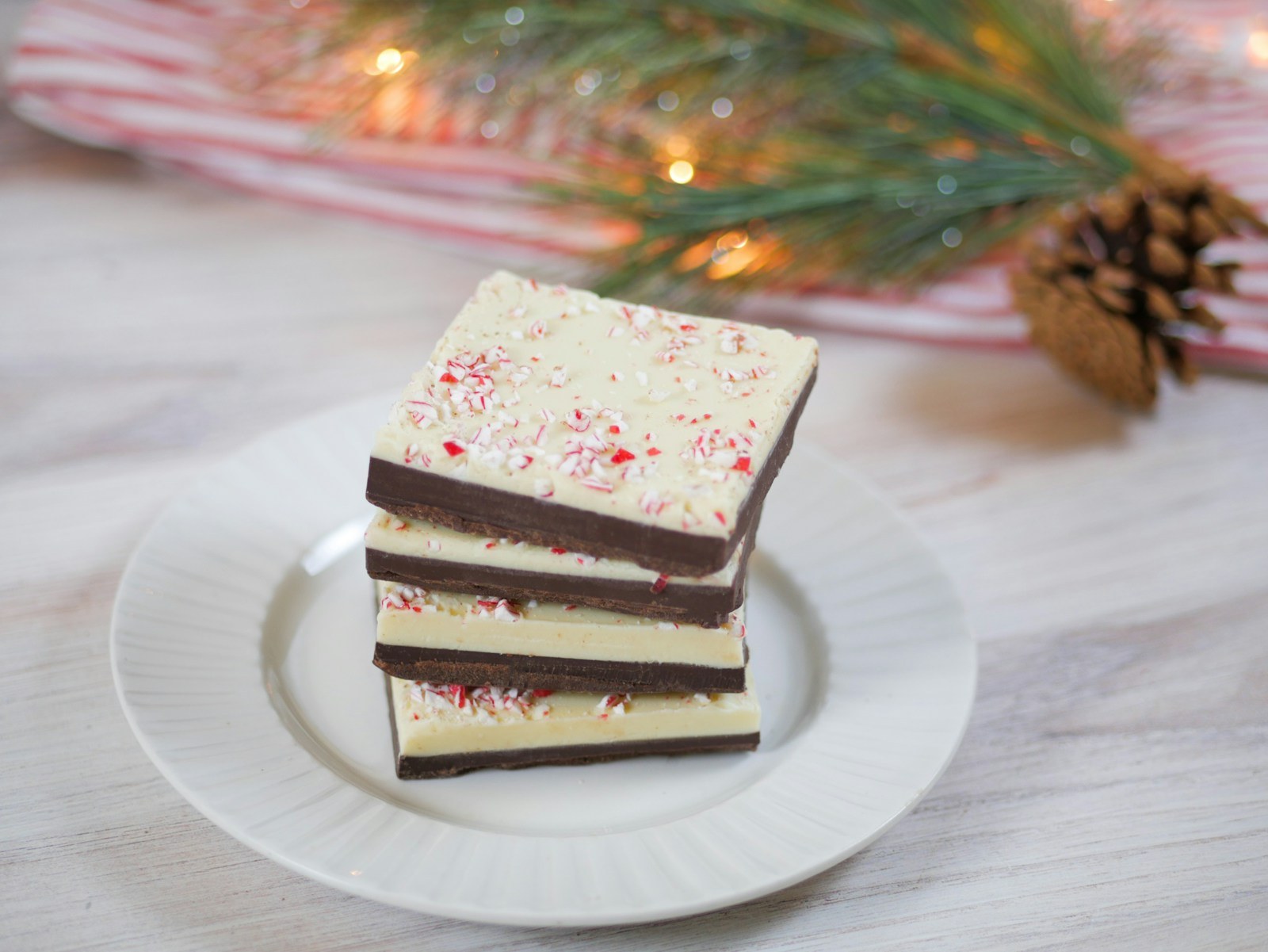 Stack of layered dark and white chocolate peppermint bark squares on a white plate