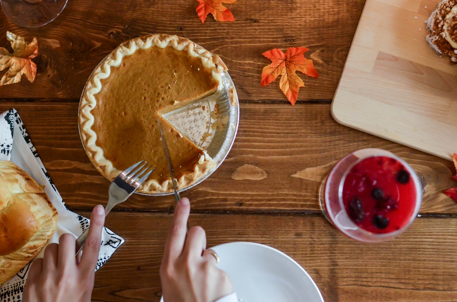 Pumpkin pie with a slice cut out on a wooden table