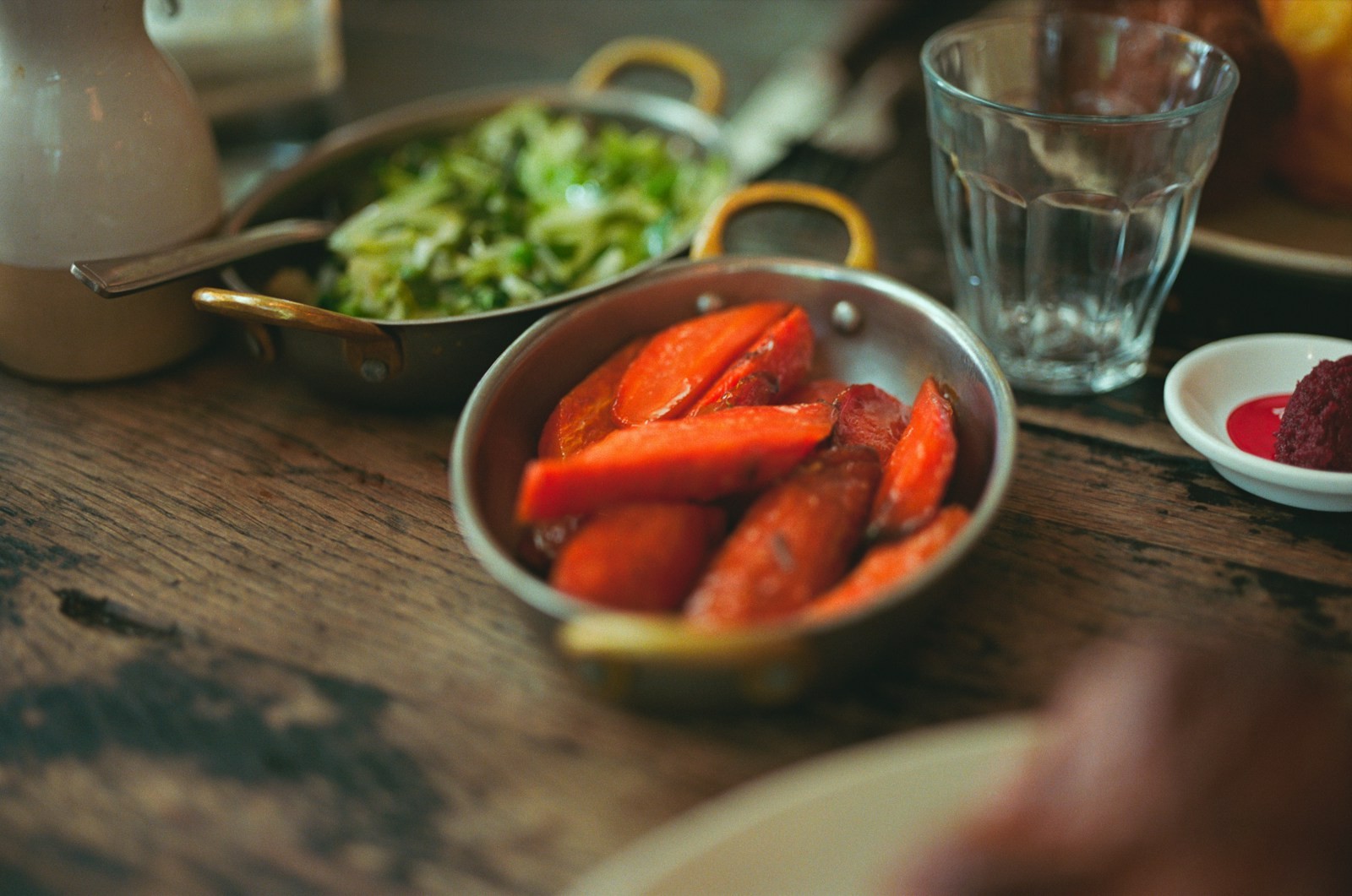 Roasted carrots glazed in a small metal pan on a wooden table