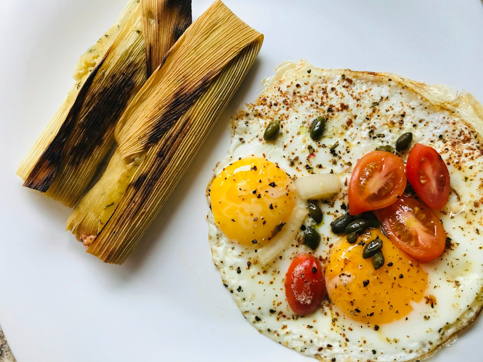 Holiday tamales in corn husks served with eggs and tomatoes