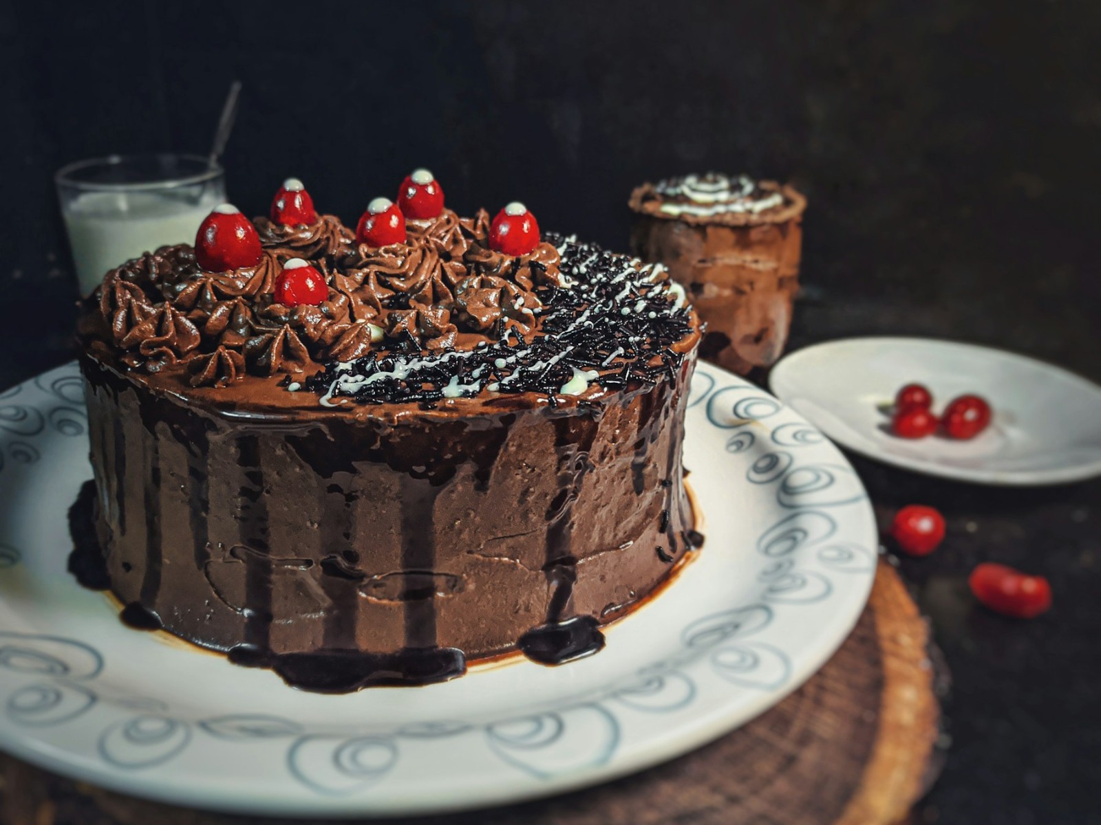 Chocolate drip cake topped with piped cream and red cherries