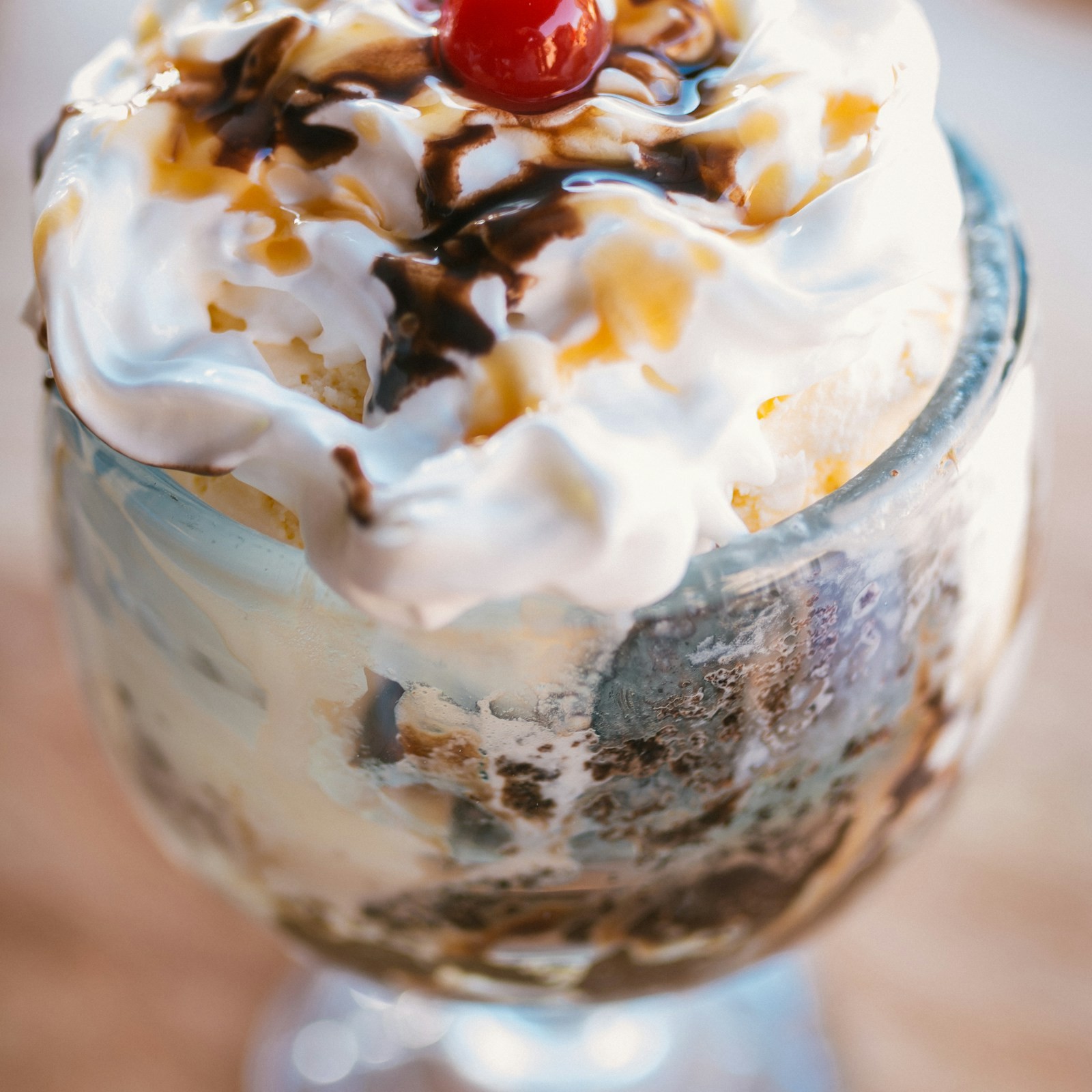 Ice cream sundae in a glass with whipped cream, chocolate sauce and a cherry