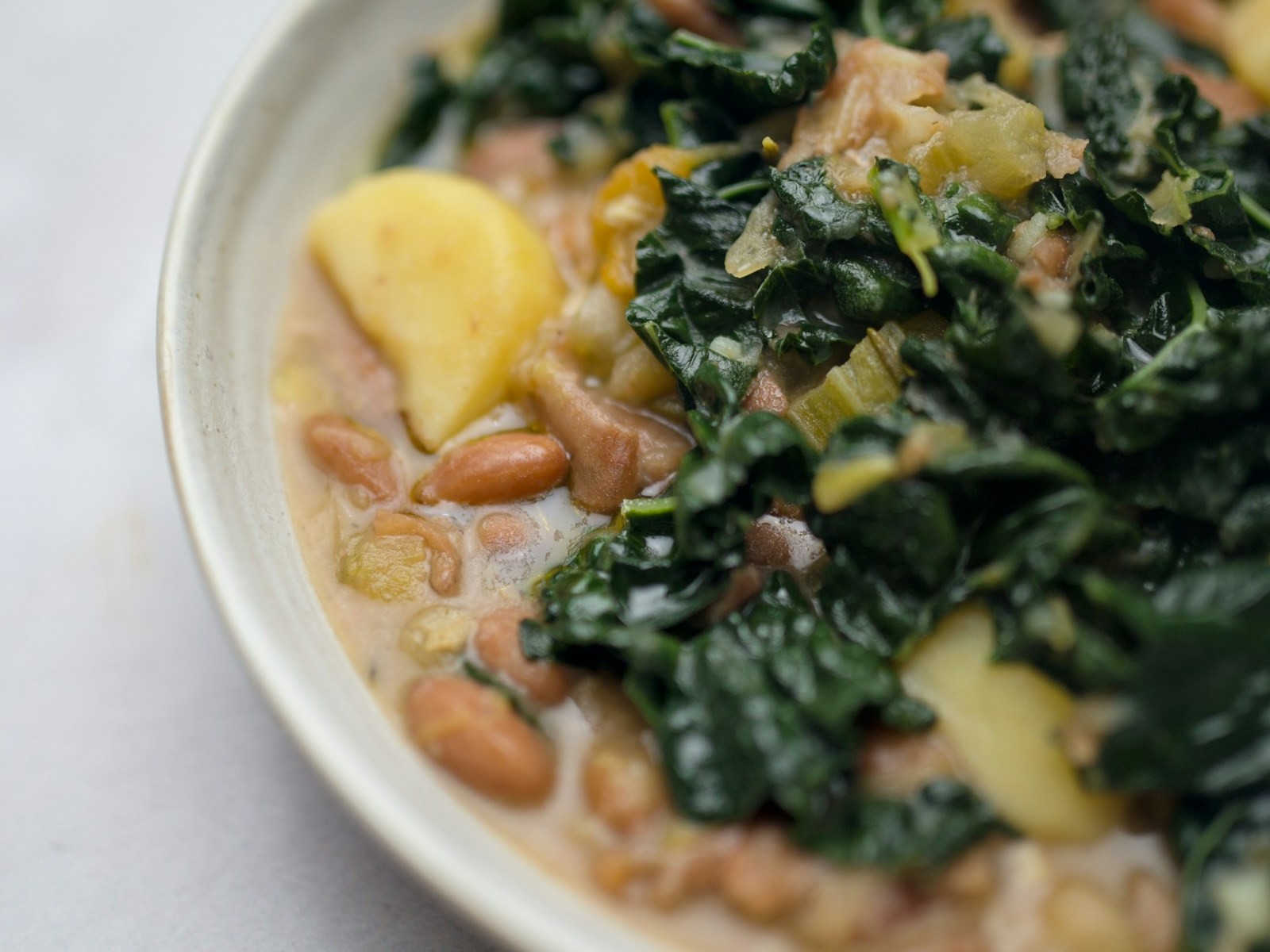 White beans with greens and potatoes in a bowl