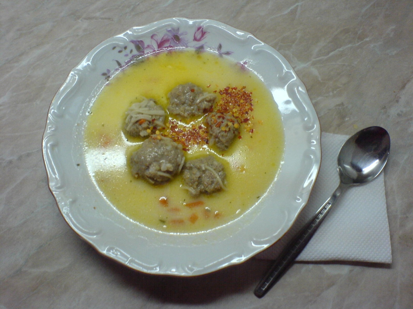 Bowl of meatball soup in a clear broth