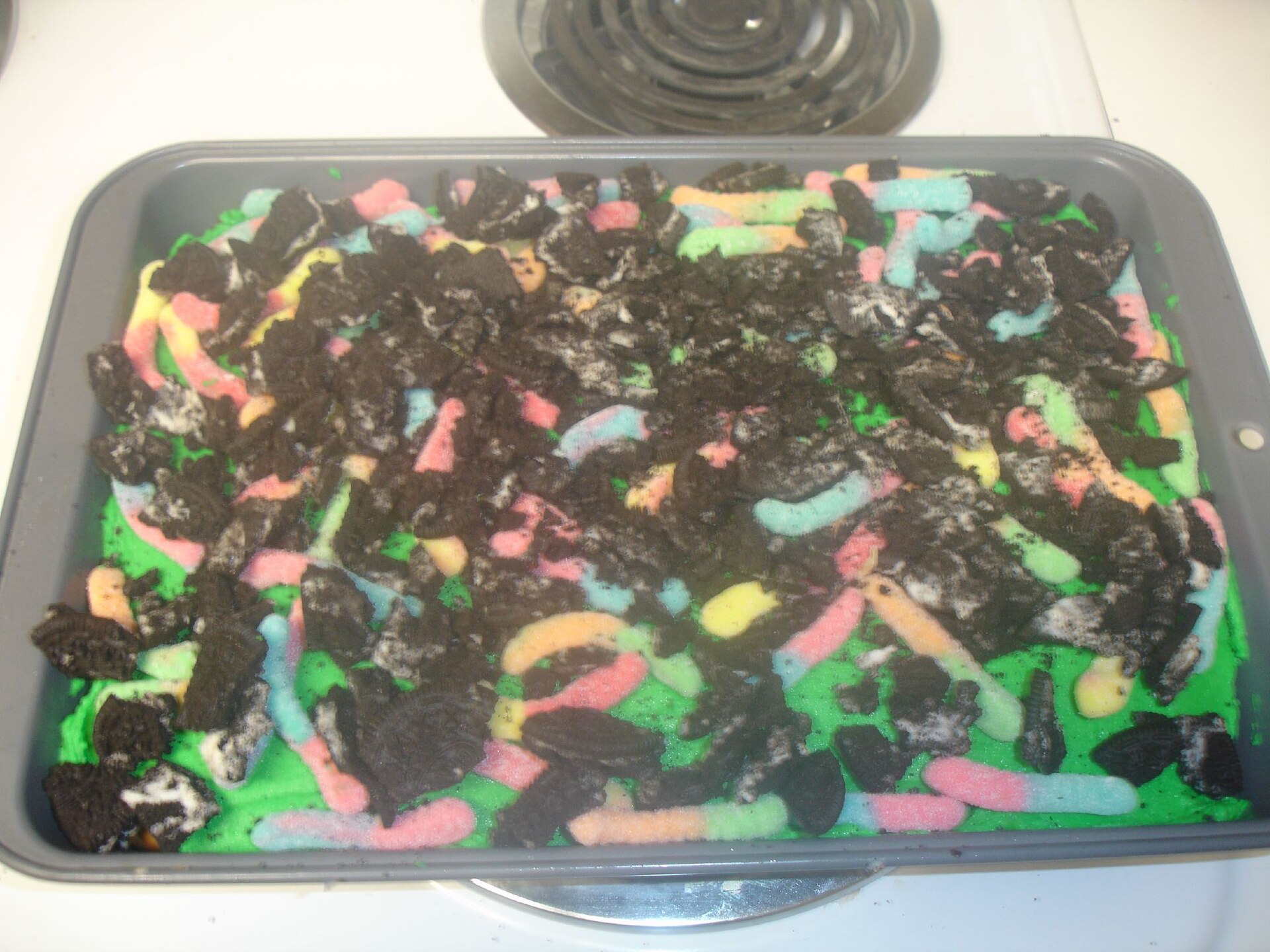 Dirt cake with crushed chocolate cookies and gummy worms in a pan
