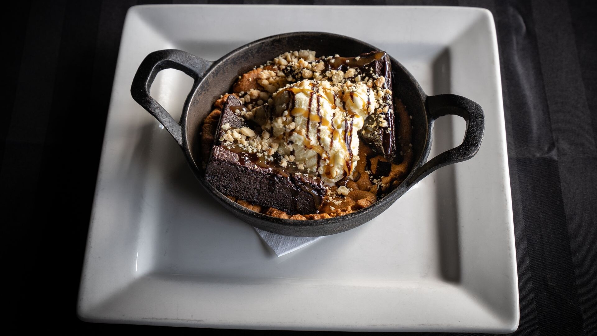 Brownie and chocolate chip skillet sundae with ice cream, caramel and chopped pecans