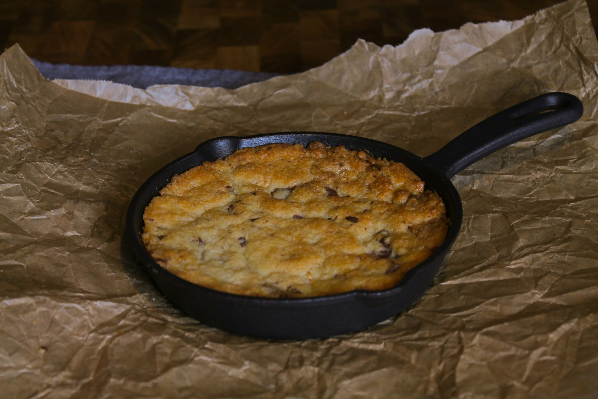 Golden chocolate chip skillet bake in a cast iron pan on parchment paper