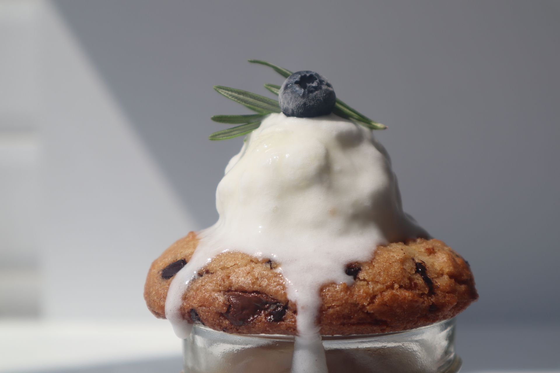 Warm chocolate chip dessert for one topped with melting vanilla ice cream and a blueberry