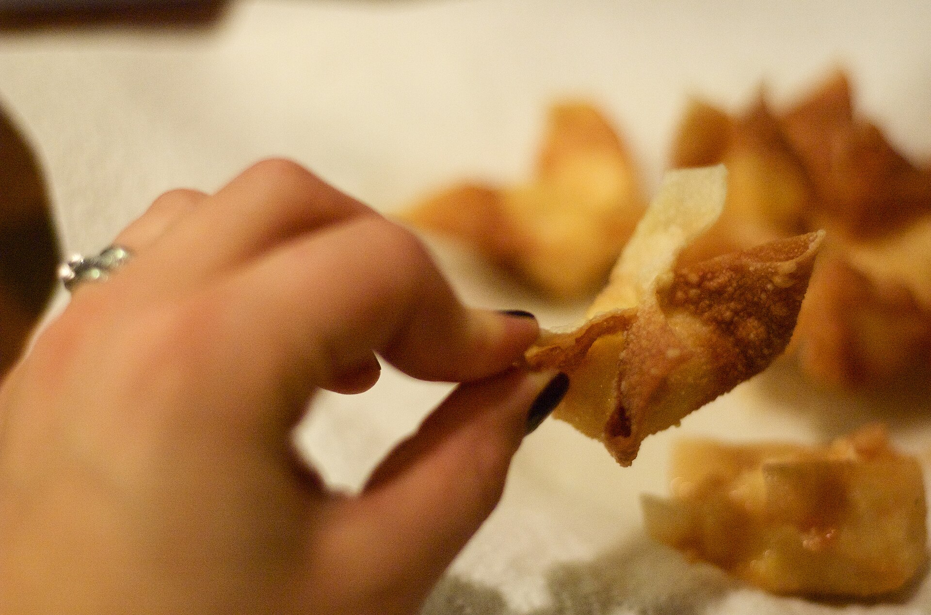 Hand picking up a crisp homemade wonton from a fresh batch
