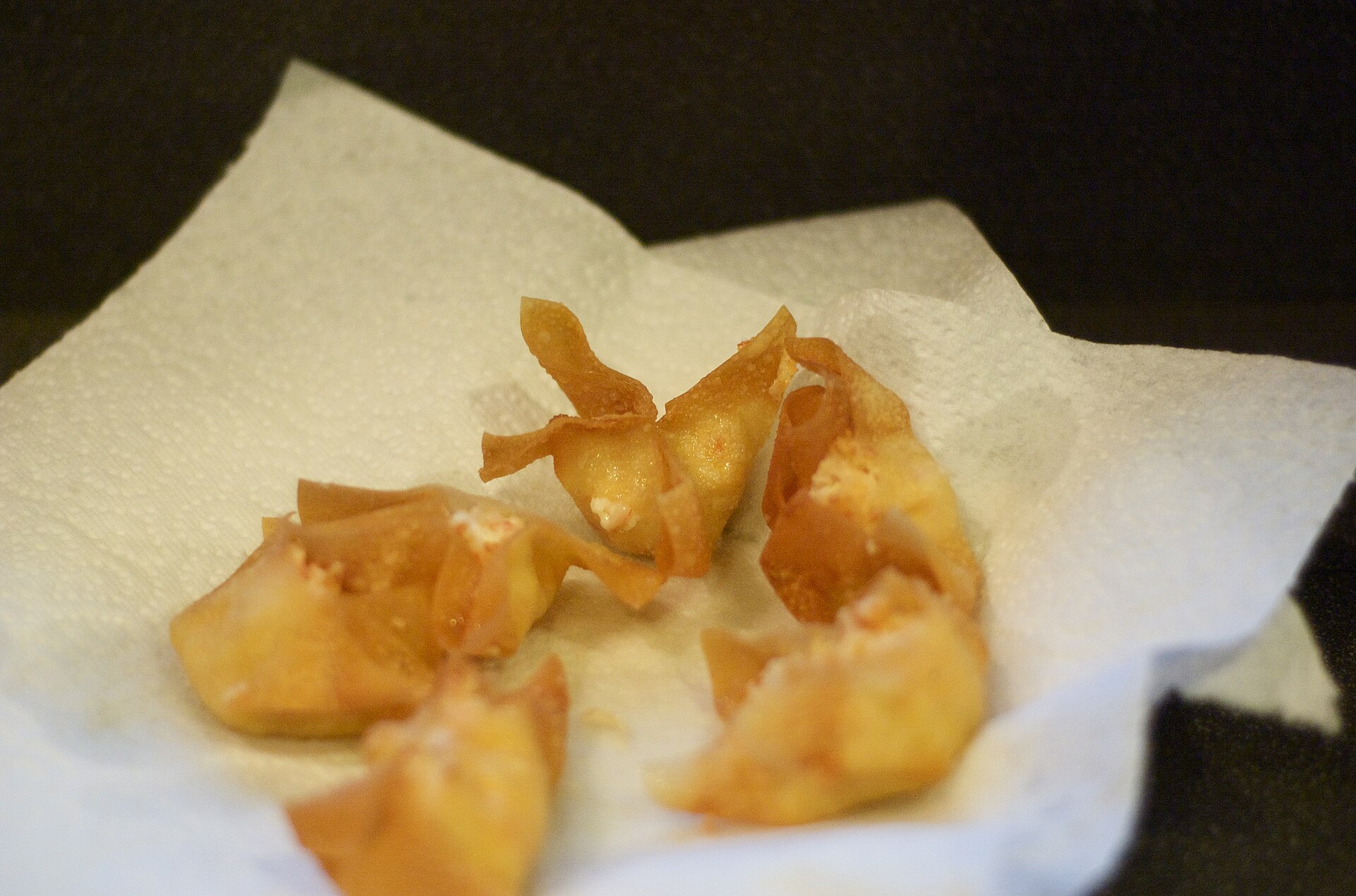 Homemade fried crab rangoon draining on a paper towel, one of the easiest crab rangoon recipes