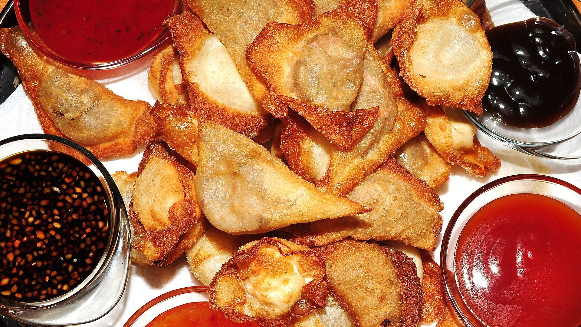 Crab rangoon recipes served on a platter with fried wontons and dipping sauces
