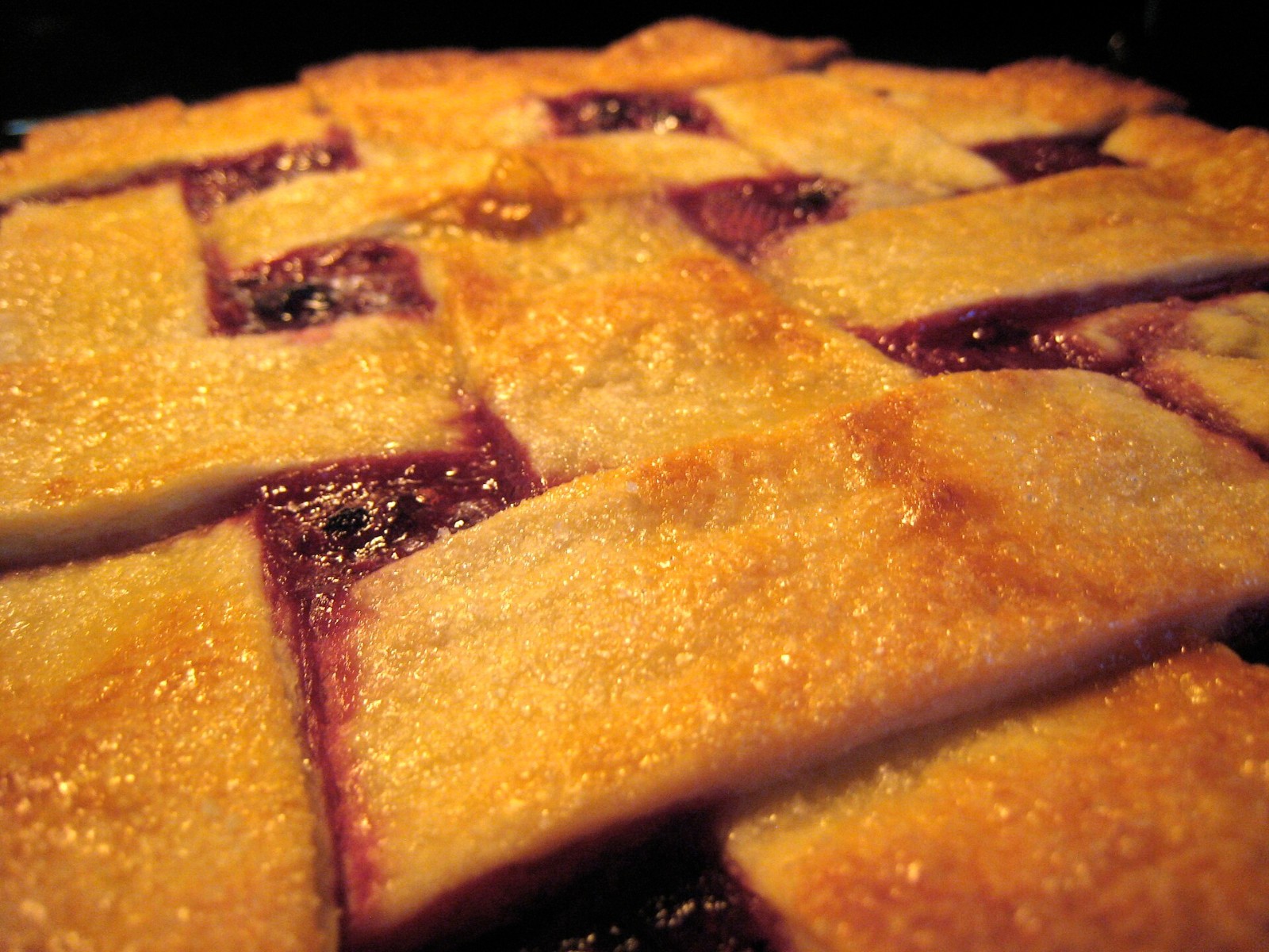 Close-up of a golden lattice over a bubbling mixed berry filling
