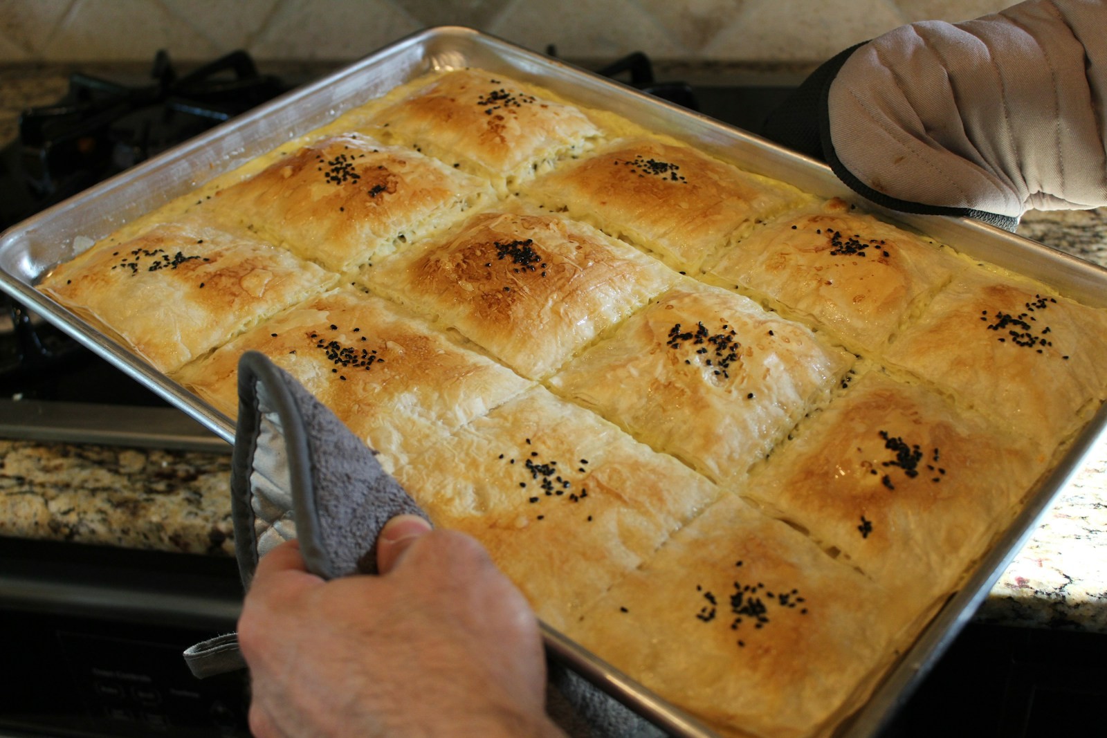 Savory pastry squares with nigella seeds on a baking tray