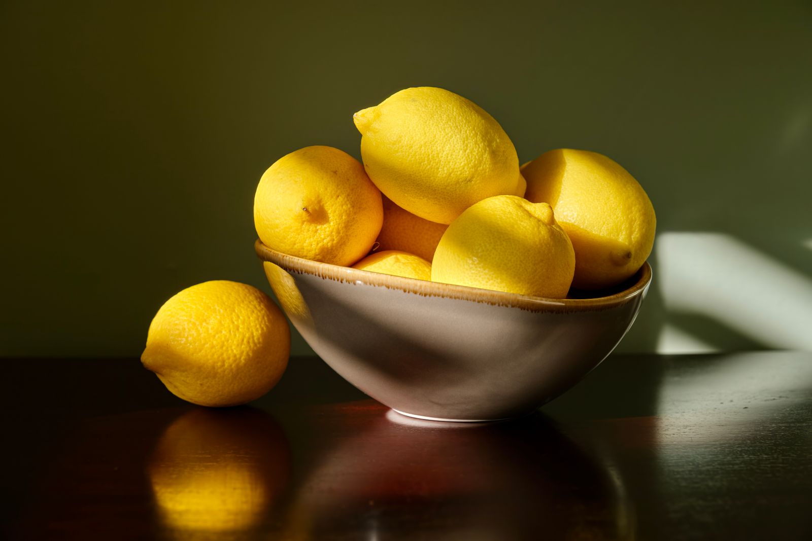 Bowl of fresh lemons on a dark table