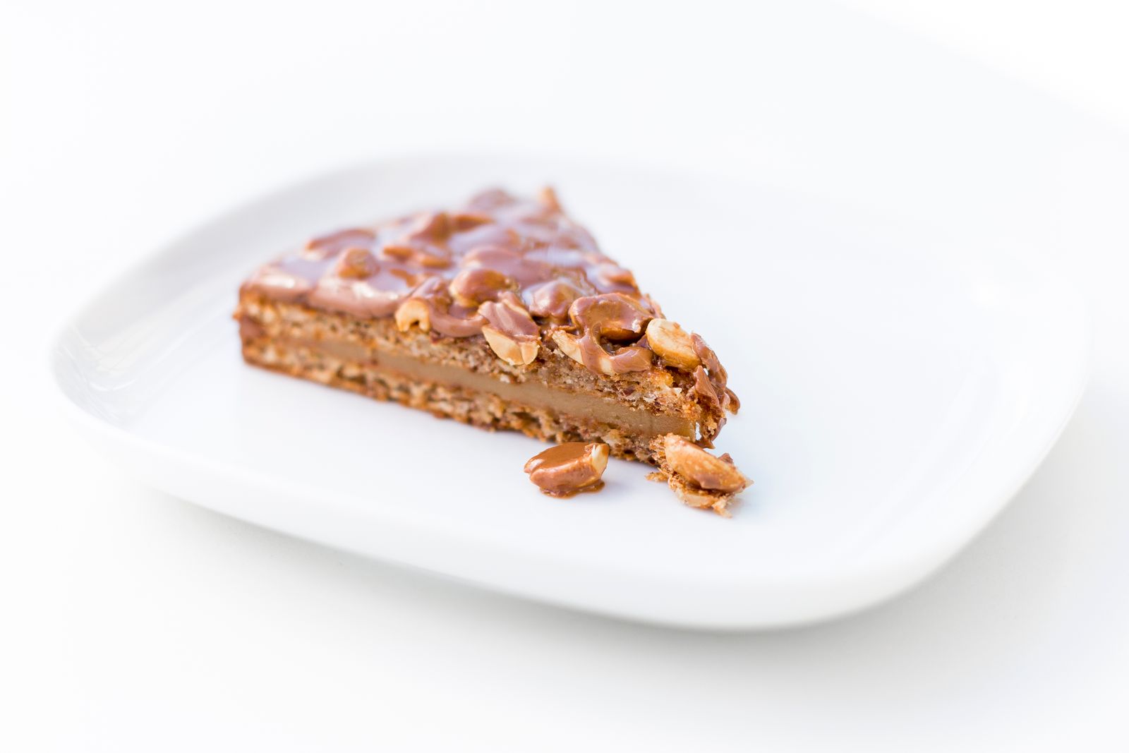 Slice of caramel nut cake on a white plate