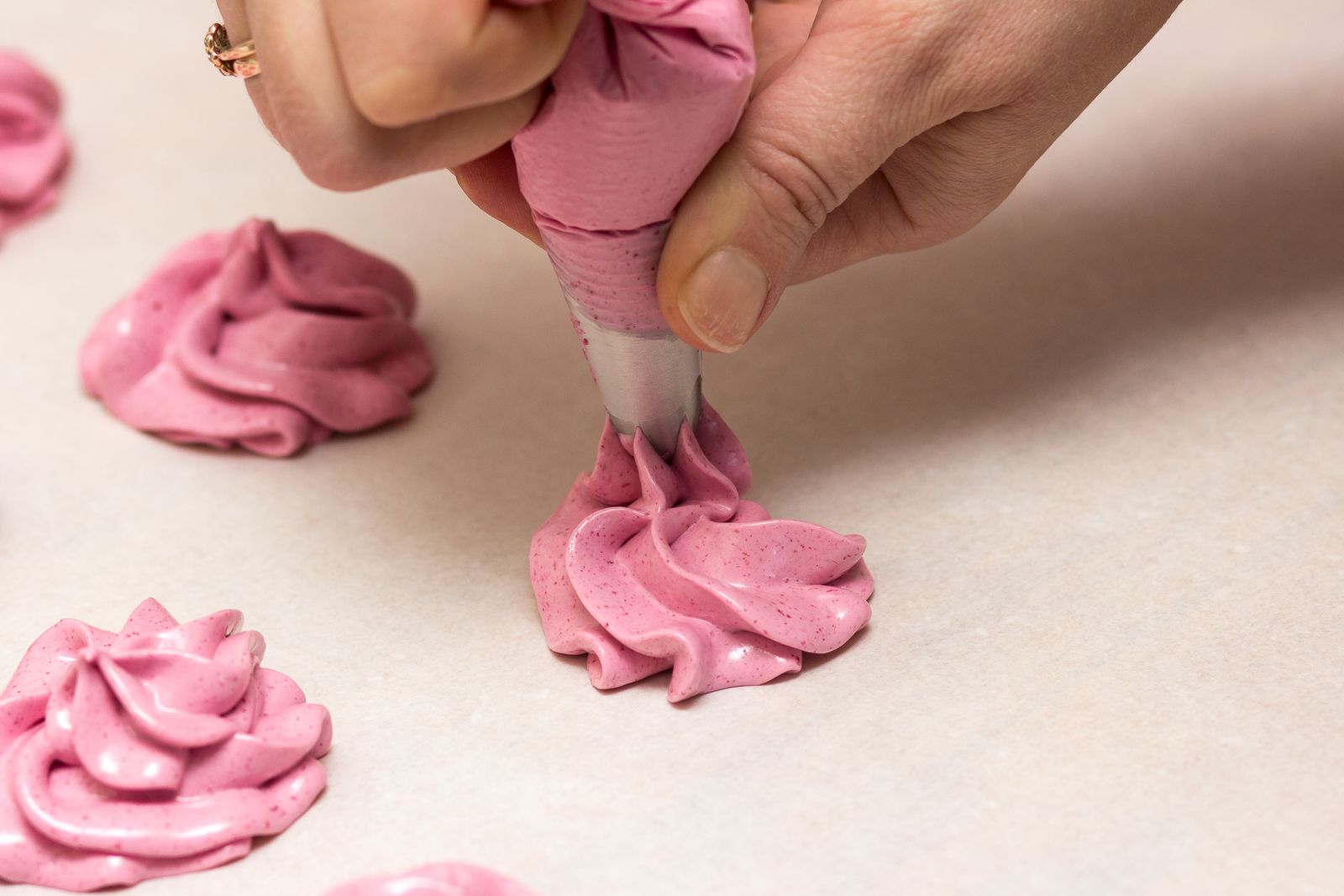 Piping pink swirls onto a tray