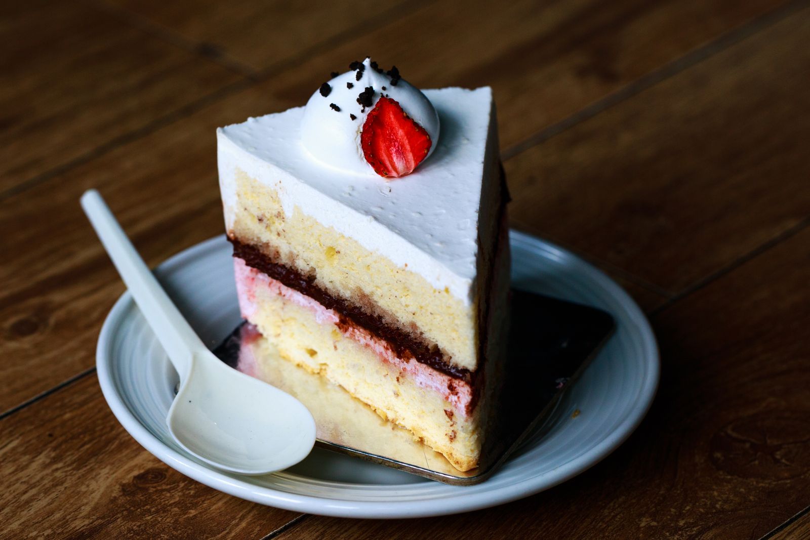 Slice of layer cake with whipped cream and a strawberry