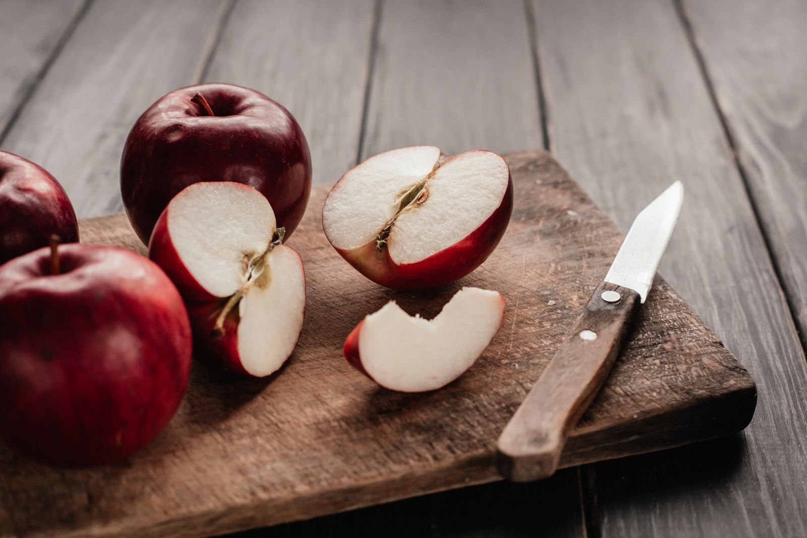 Red apples sliced on a wooden cutting board