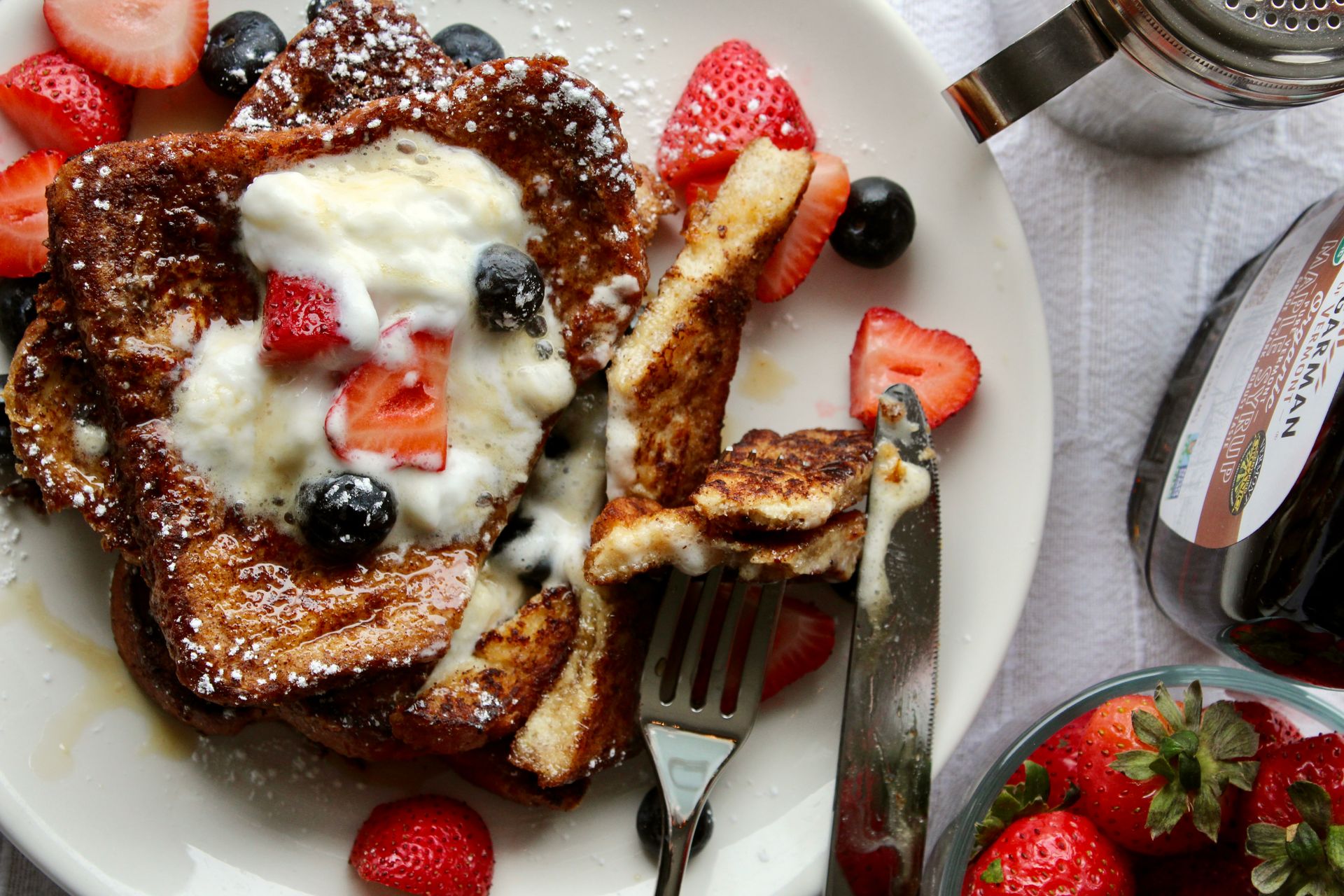 French toast with berries and whipped cream on a plate