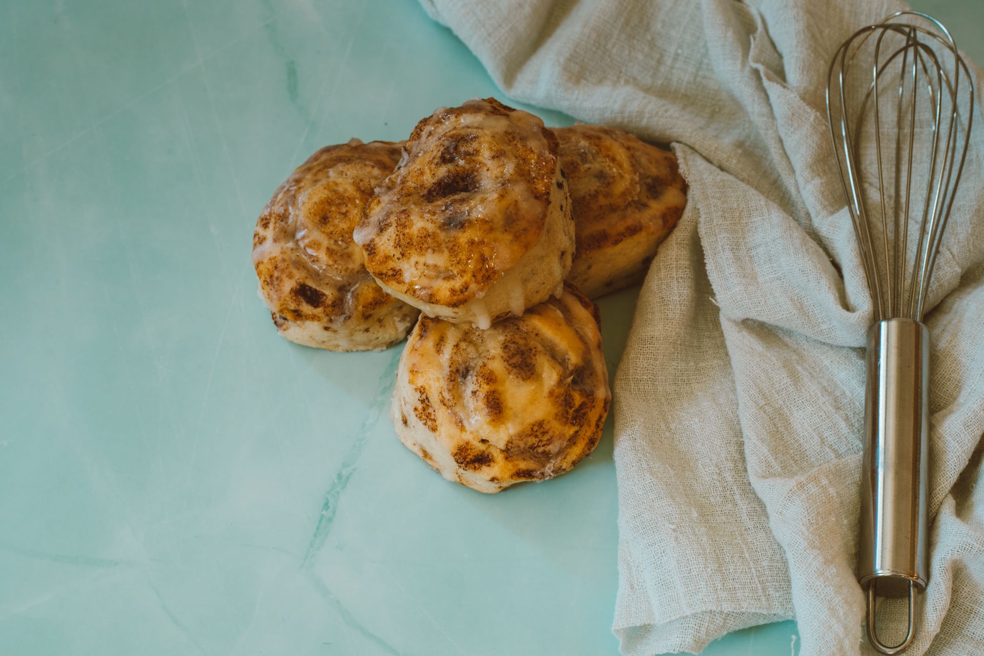 Freshly baked buns with a whisk on a kitchen cloth