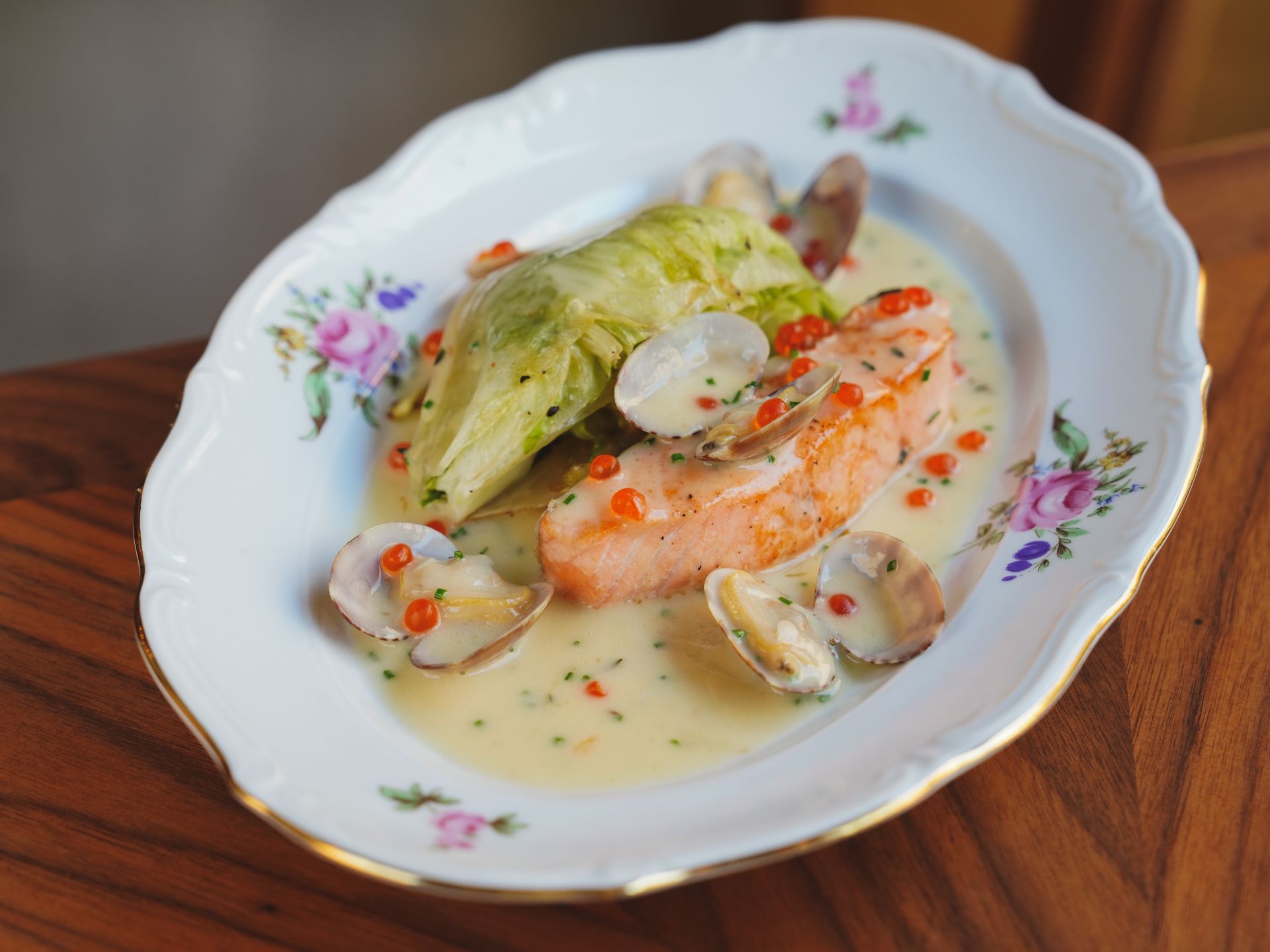 Creamy salmon with clams in a white wine cream sauce on a floral plate