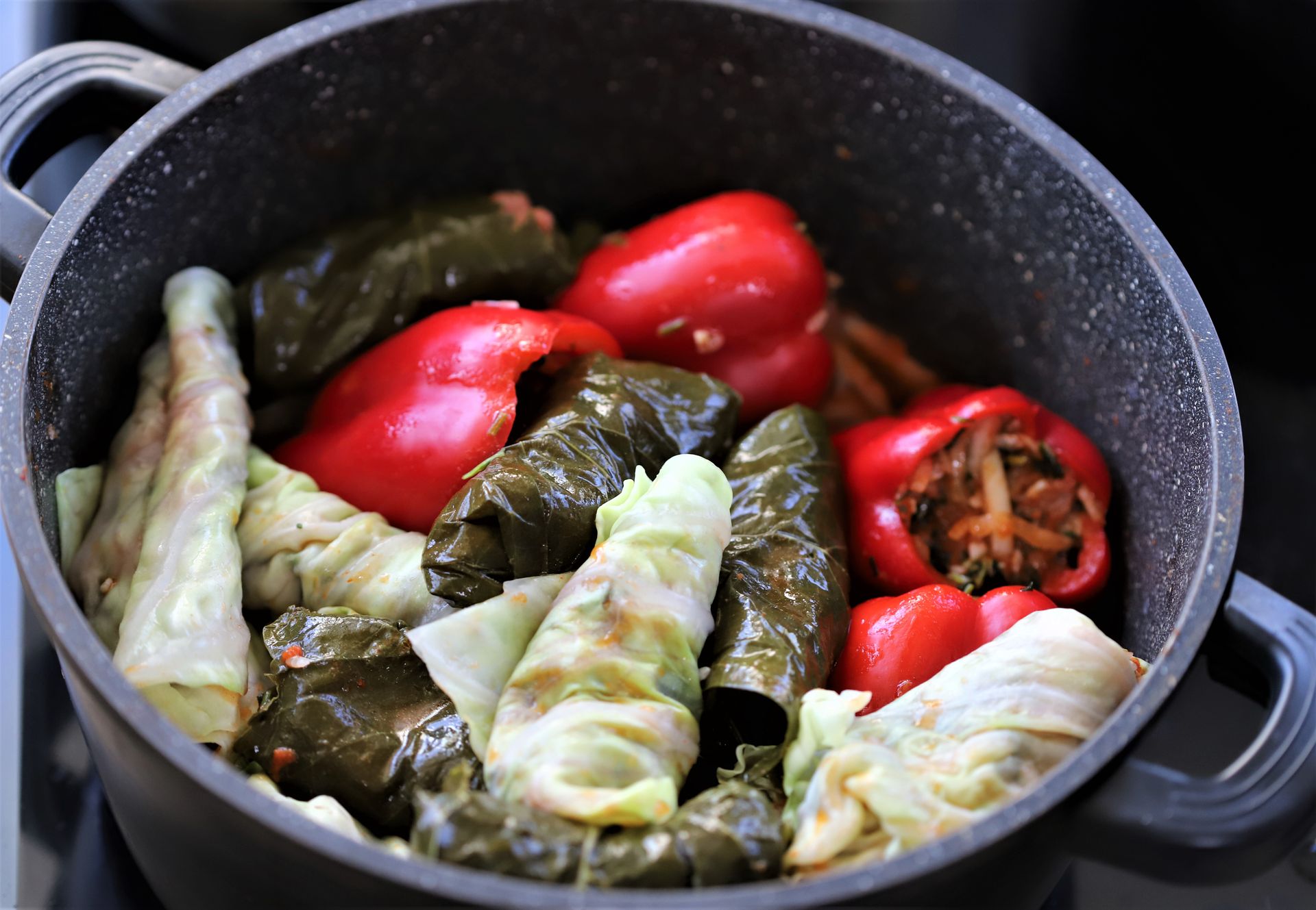 Cabbage rolls and stuffed peppers simmering together in a pot