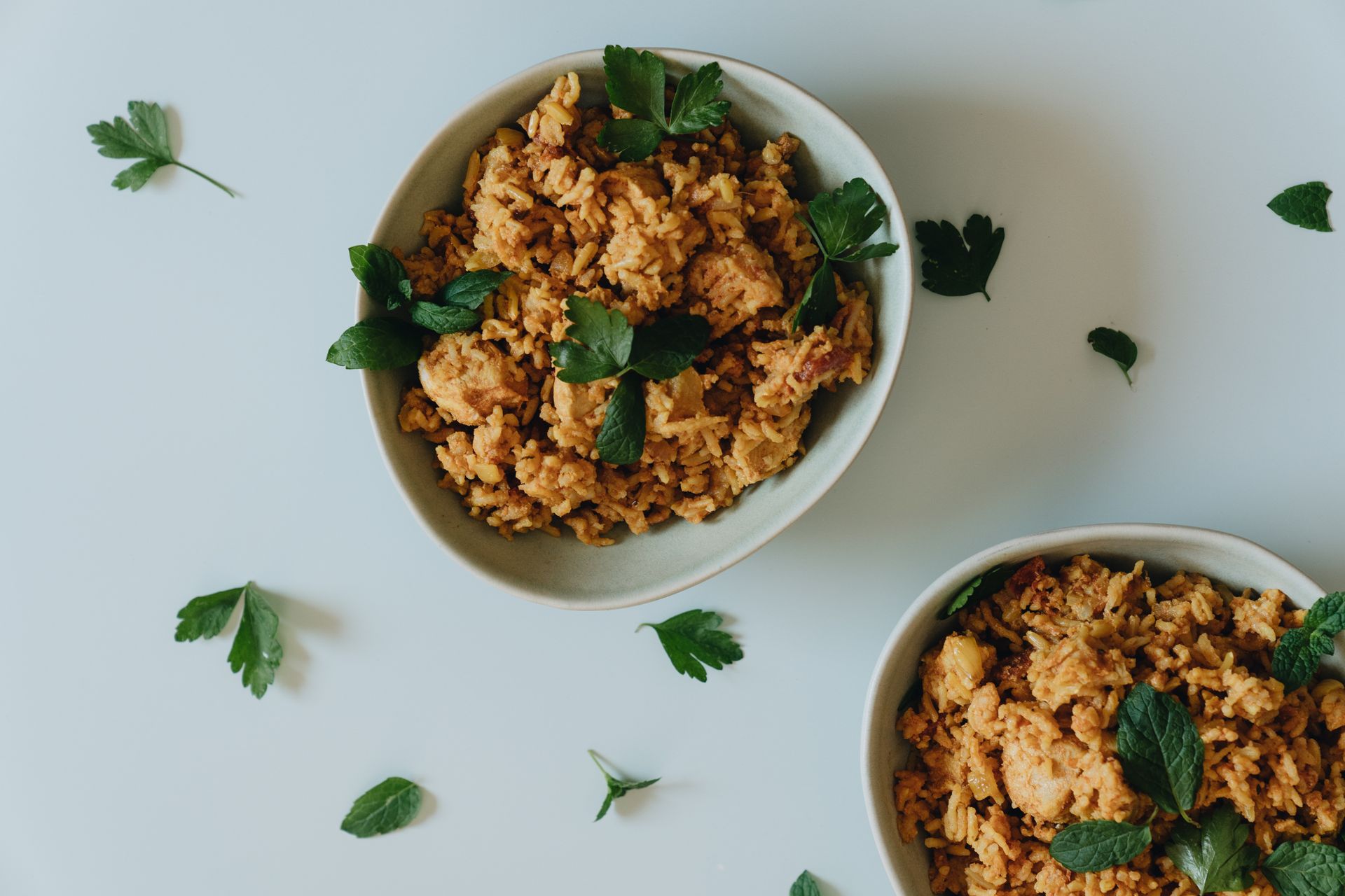 Two bowls of spiced Cajun-style grains with meat and fresh herbs