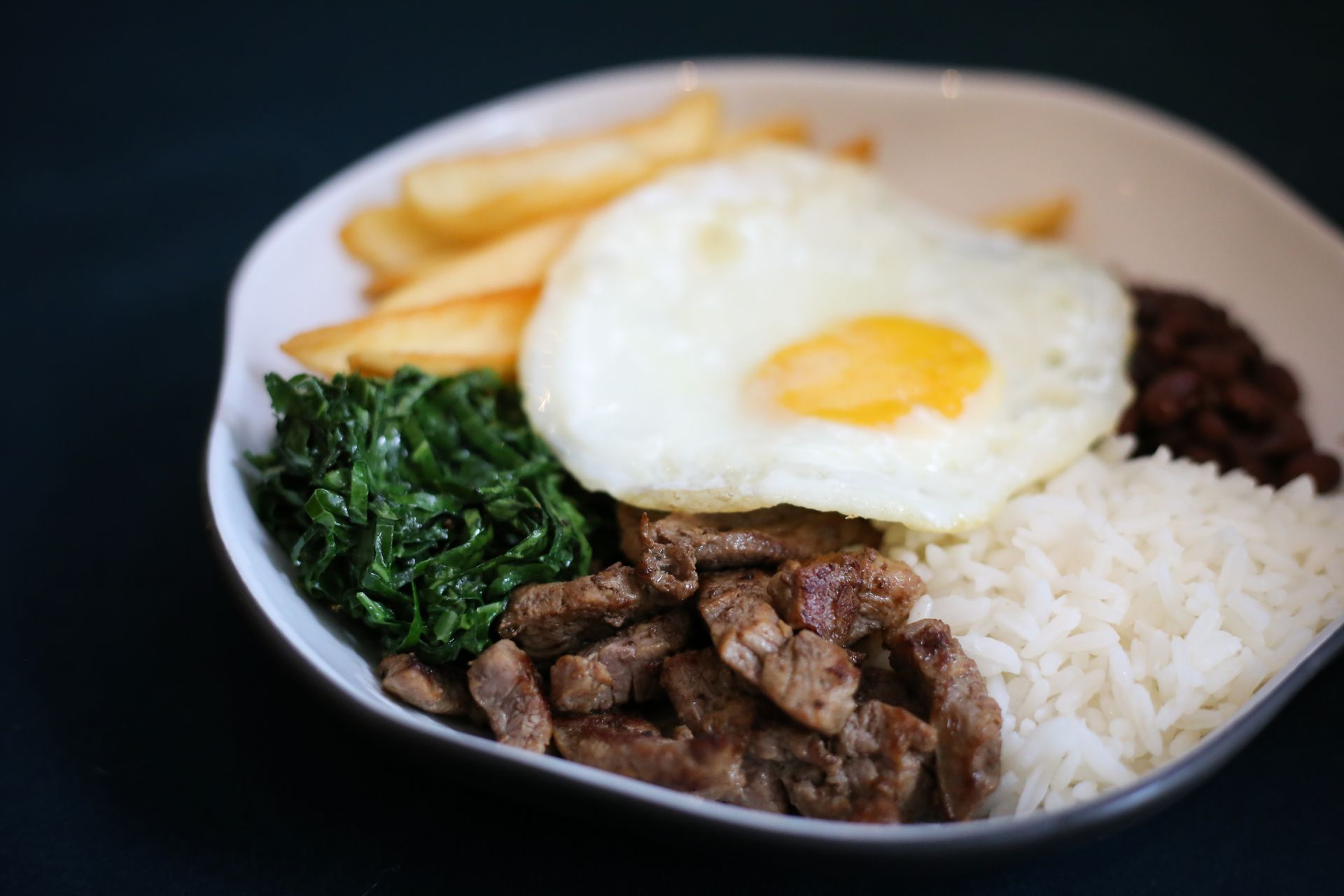 Plate of seared meat, greens and a fried egg