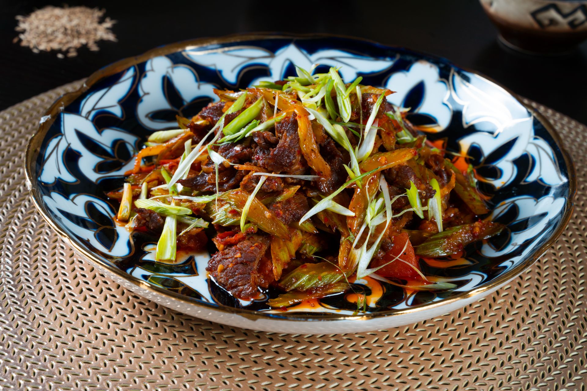 Stir fried meat with peppers and green onions in a patterned bowl