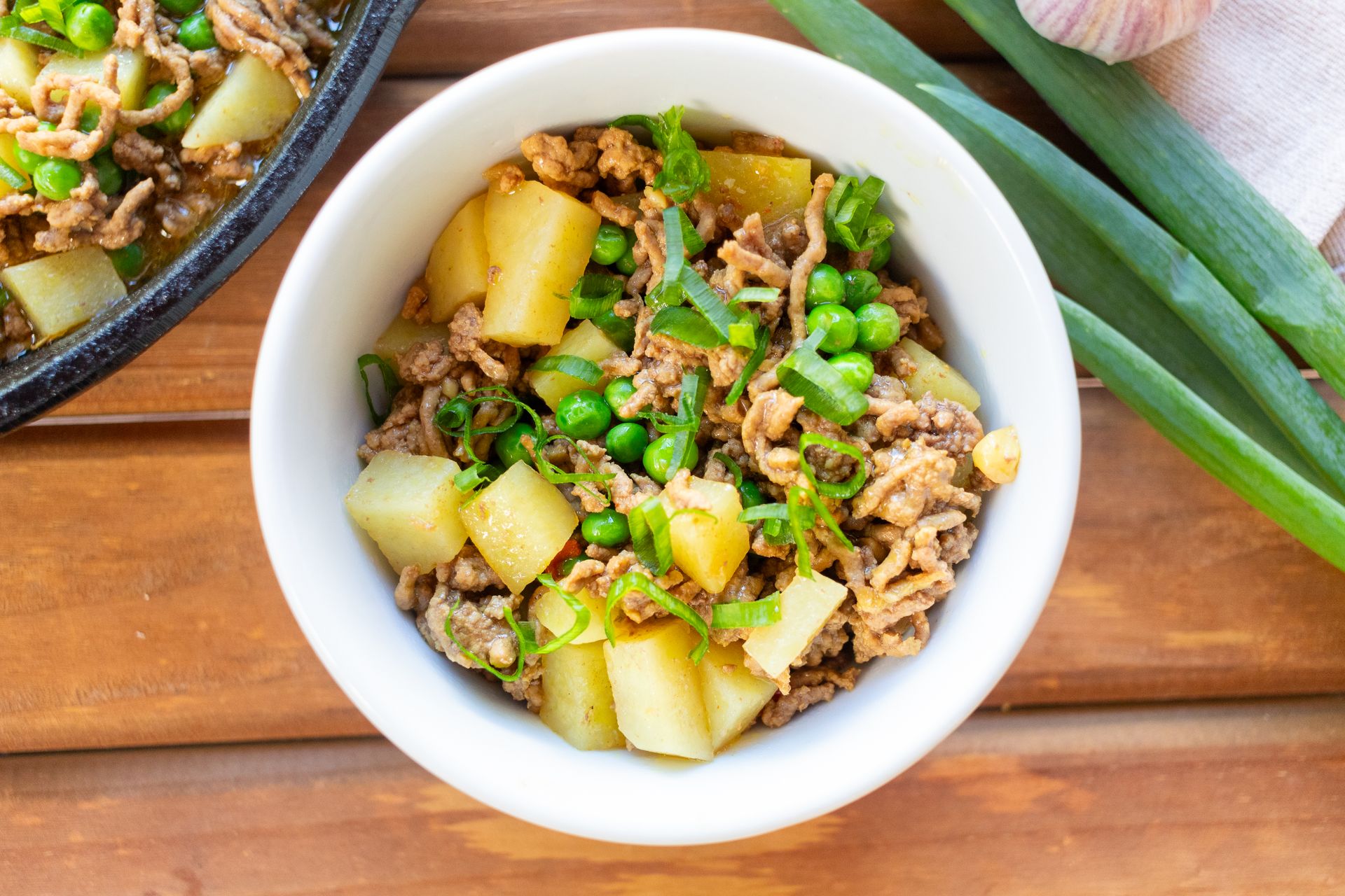 Minced meat stew with potatoes and peas in a white bowl