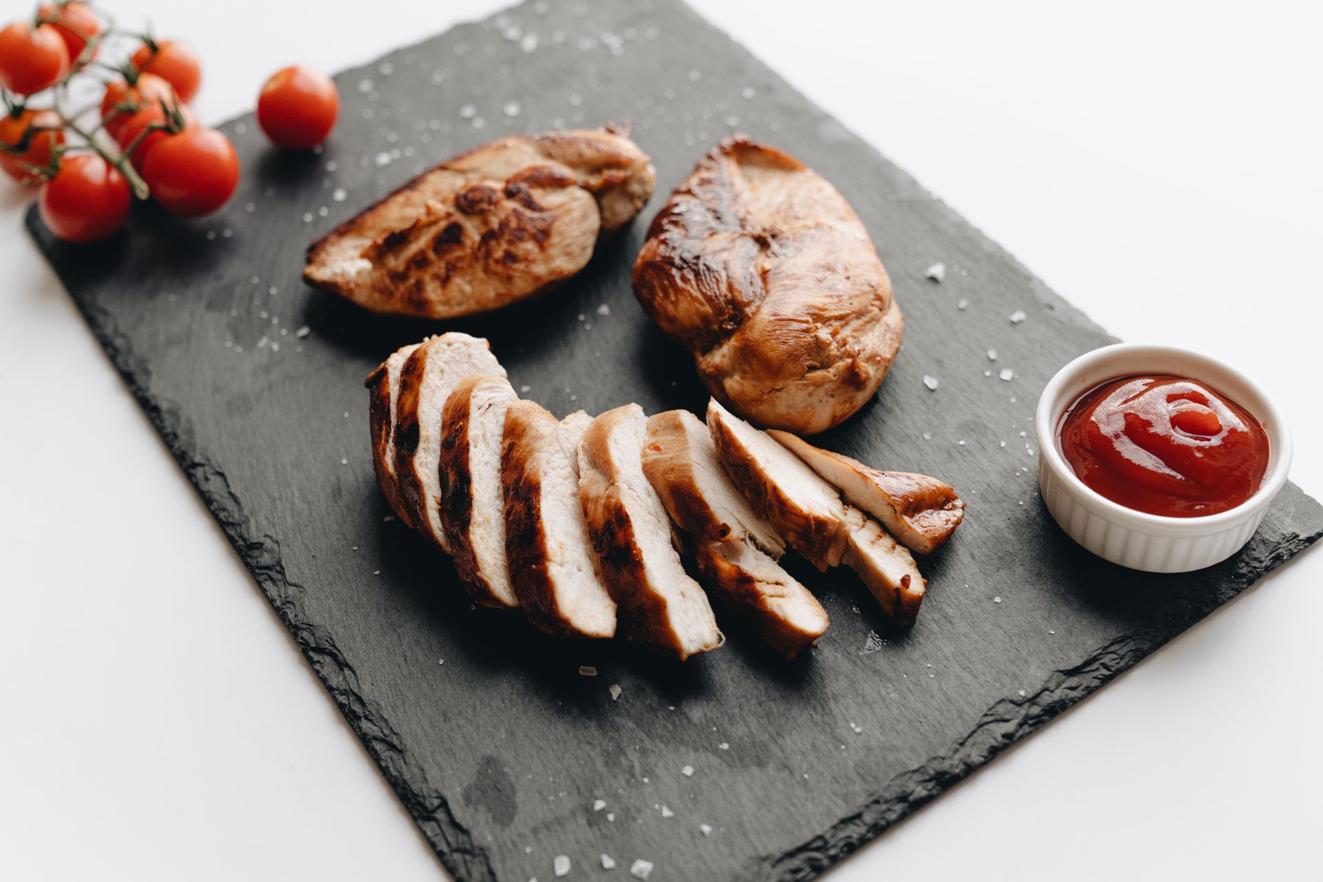Sliced seasoned chicken breast on a dark slate board