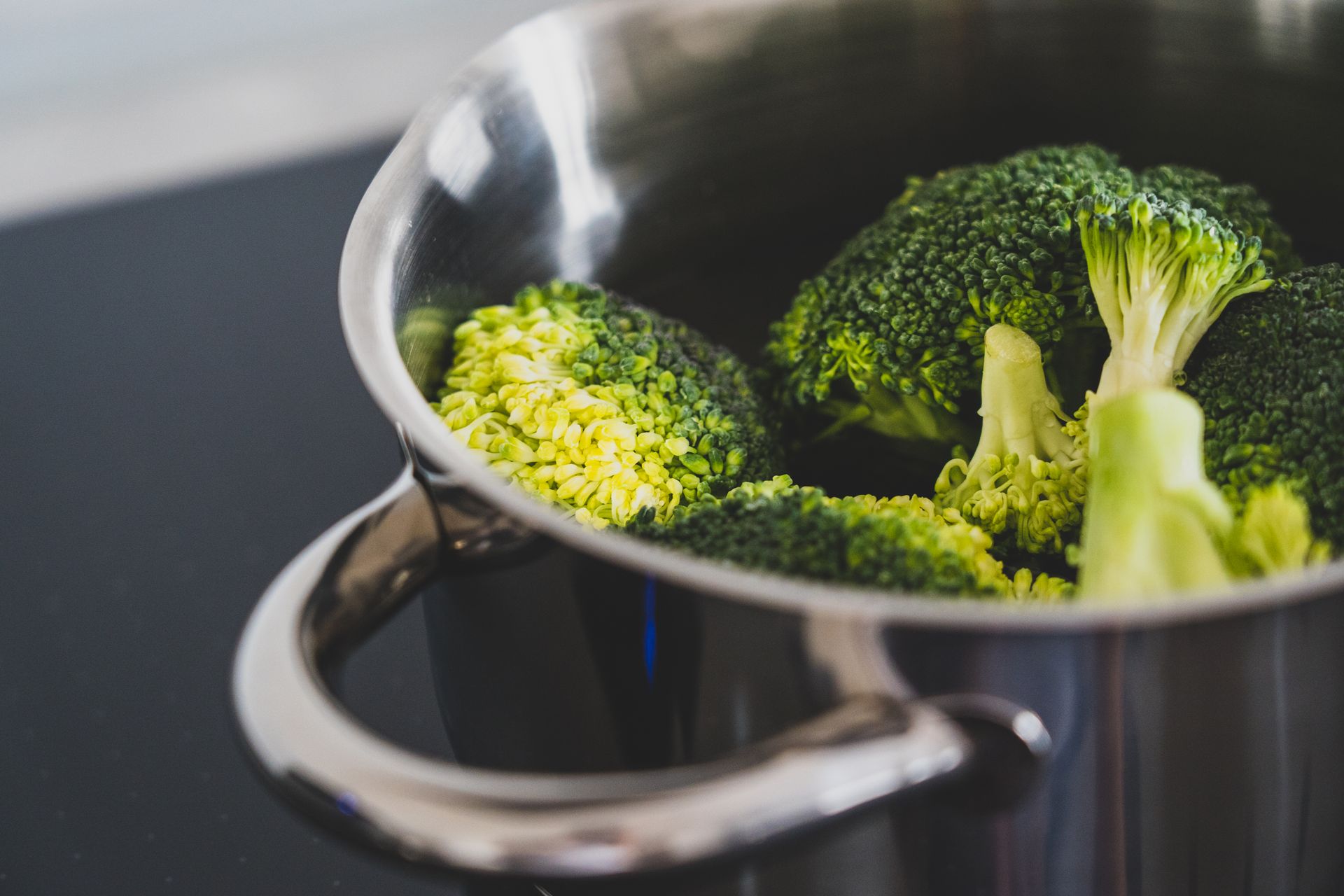 Green broccoli steaming in a stainless steel cooker