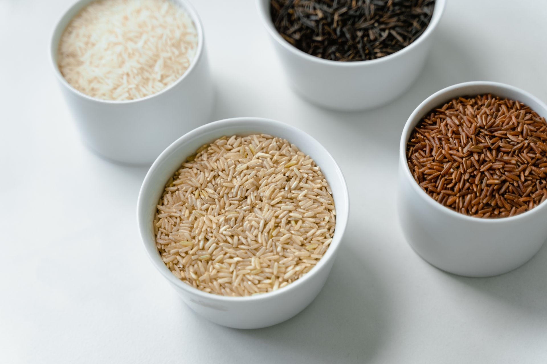 Bowls of white, brown, black and red grains lined up side by side