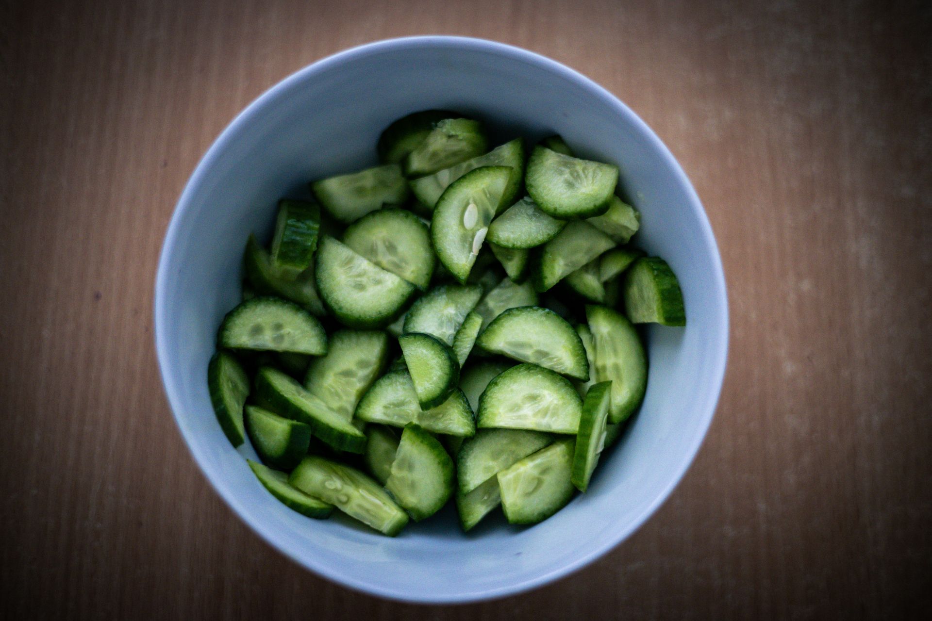 Thinly sliced cucumber salad in a blue bowl