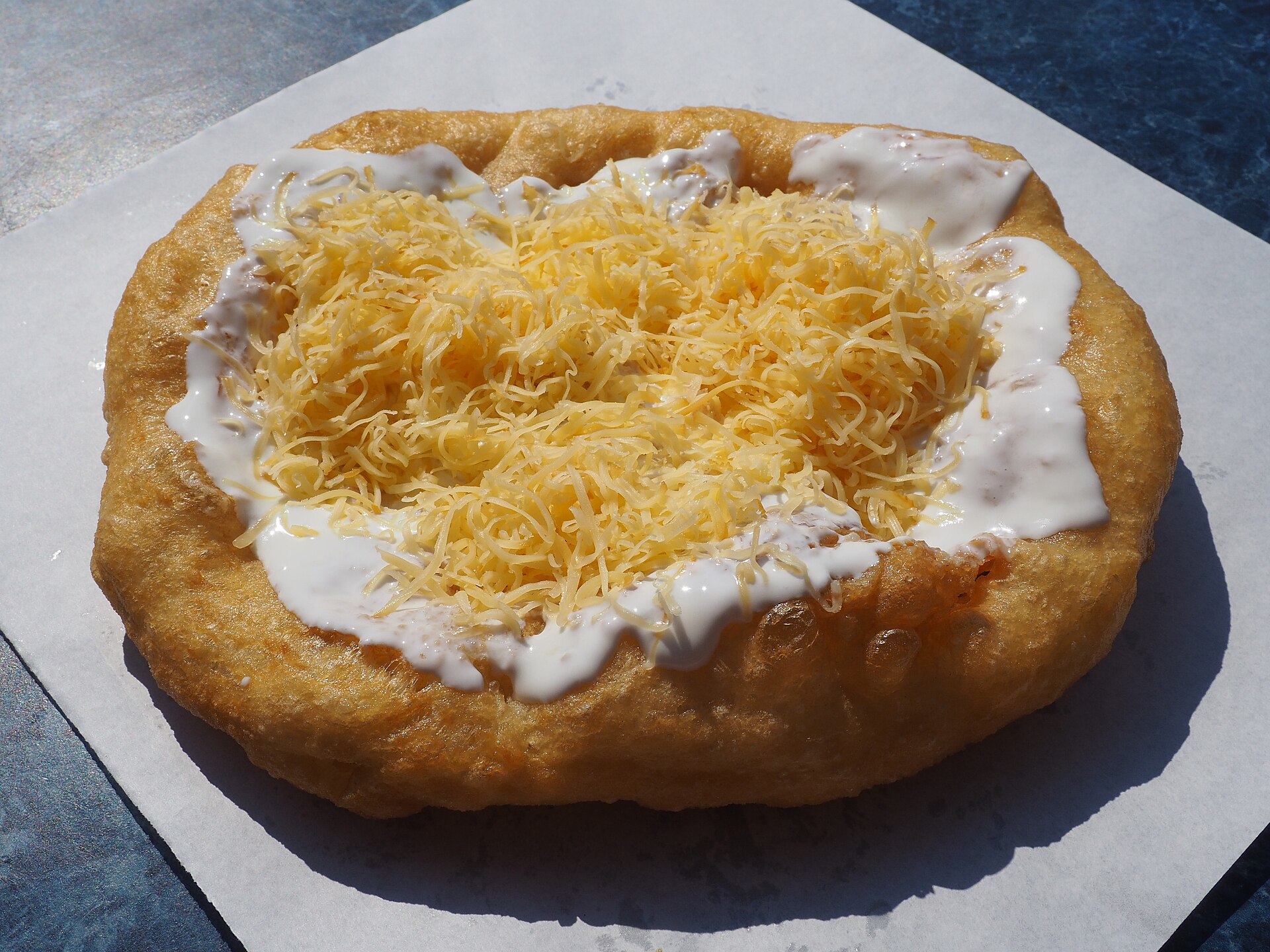 Hungarian recipes: langos fried bread topped with sour cream and grated cheese