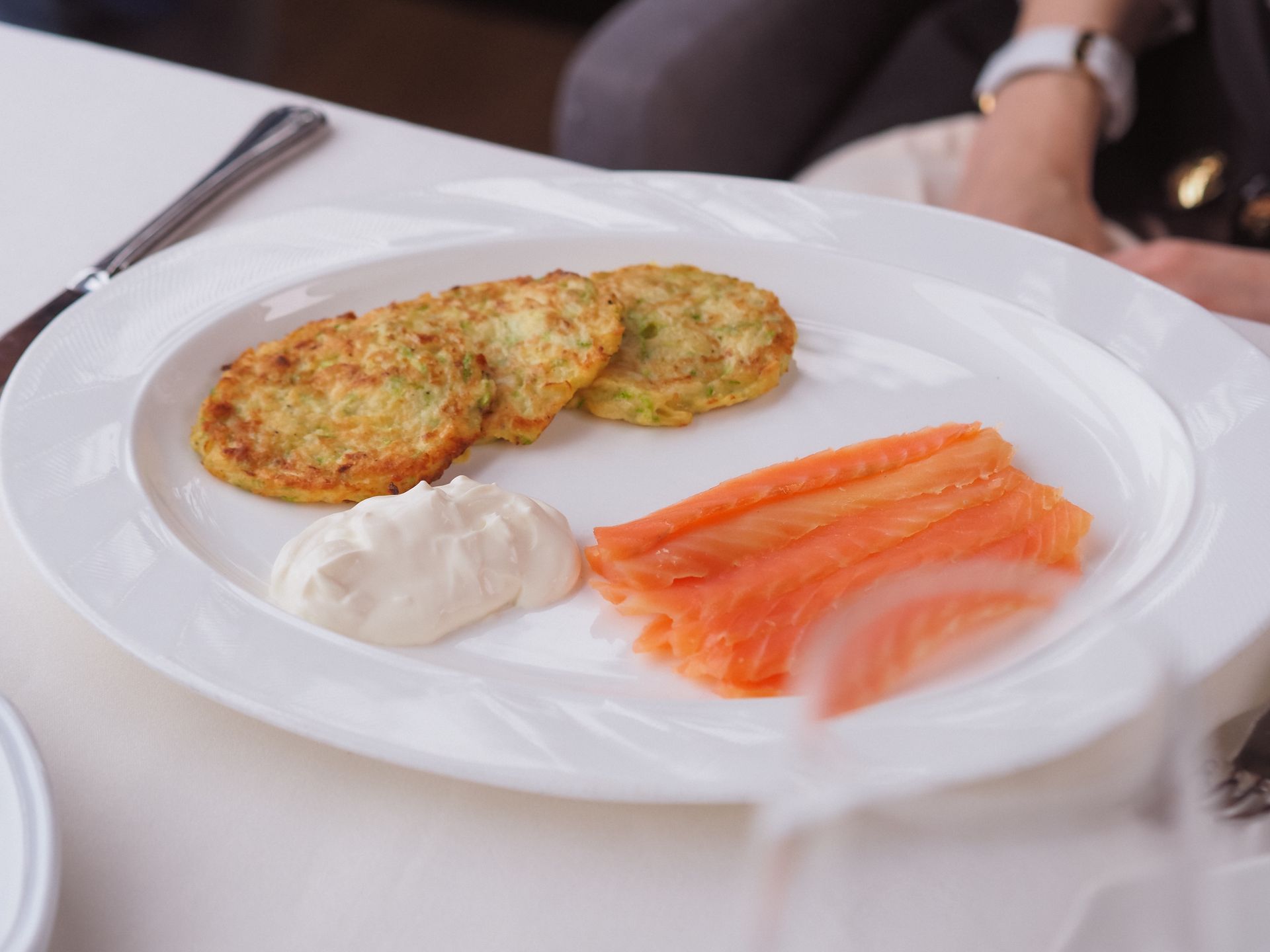 Potato pancakes with smoked salmon and sour cream on a white plate
