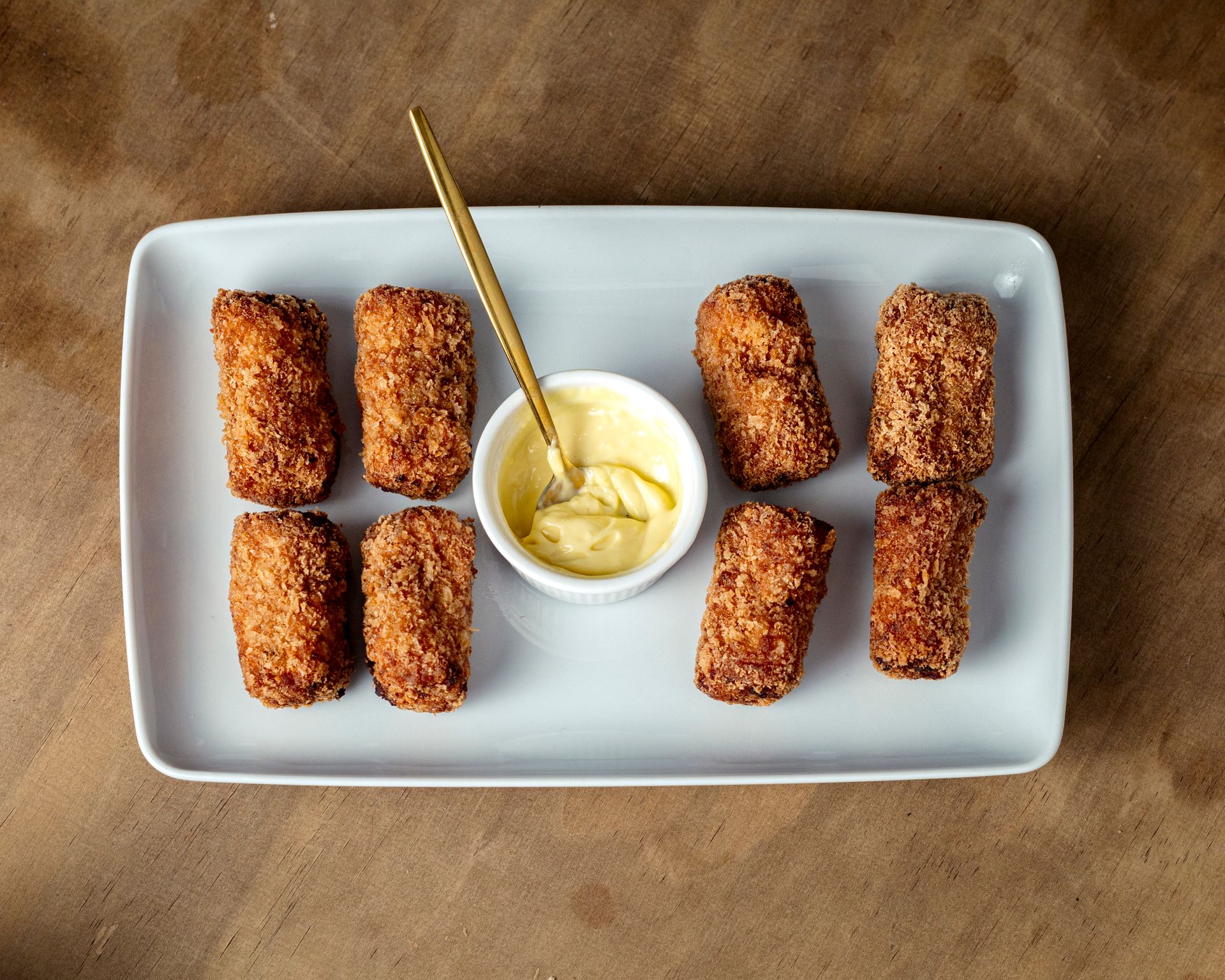 Crispy potato croquettes with a dipping sauce on a white plate